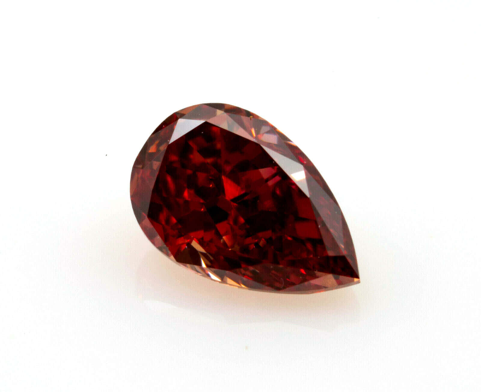 Red Diamond 桌布 壁紙 — 一顆鮮明切割的梨形紅寶石，帶有深紅色的刻面，在純白背景上閃耀。