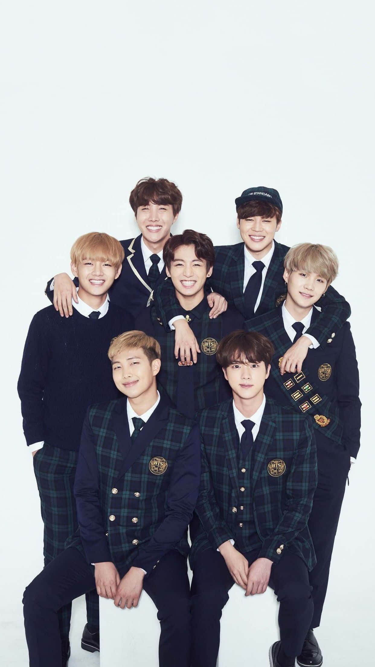 Bangtan Sonyeondan 桌布 壁紙 — 七位微笑的年輕男性穿著相配的深色格子校服，在純白色背景前一起擺姿勢。