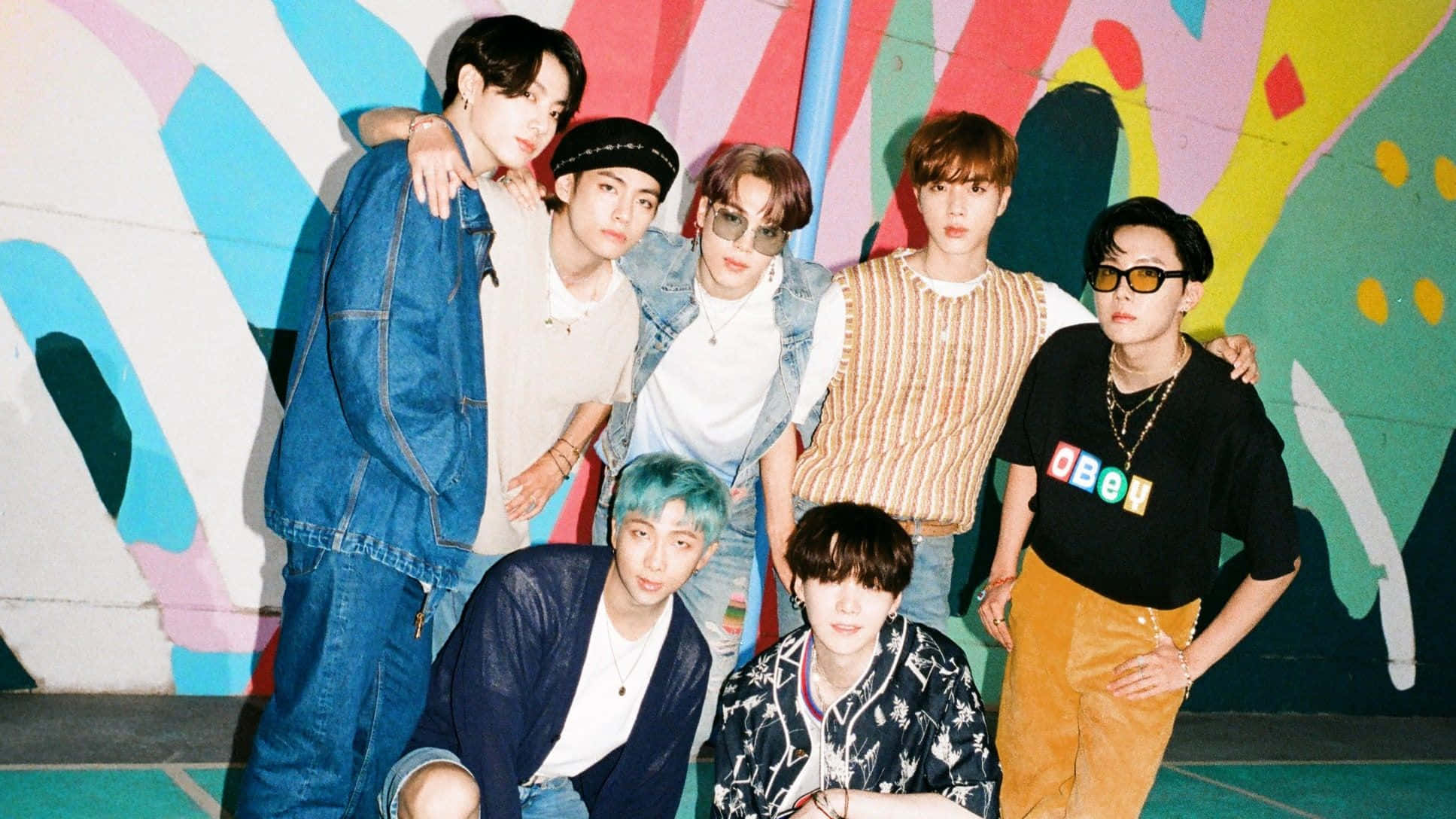 BTS - 壁紙 — 七位時尚年輕男士自信地站在充滿活力的塗鴉牆前，牆上有大膽的抽象色彩。