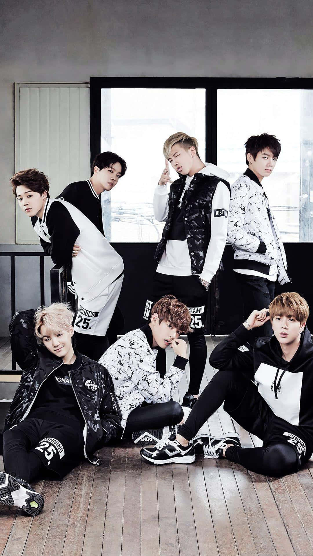 Bangtan Sonyeondan 桌布 壁紙 — 七位時尚年輕男士身穿黑白街頭服飾，在木地板上靠近大窗戶自信地擺姿勢。