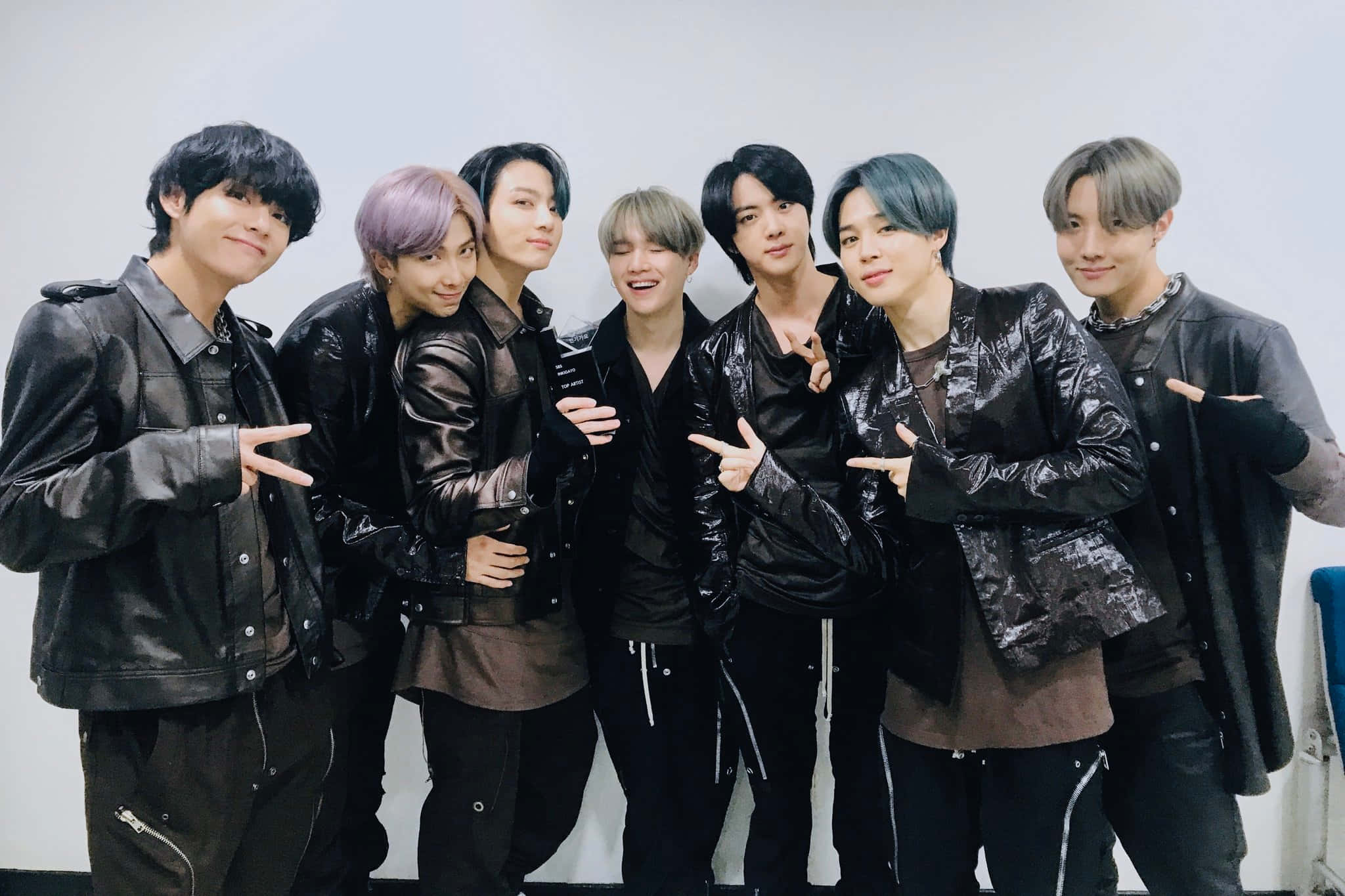 Bts Performance 桌布 壁紙 — 七位時尚年輕男士身穿黑色皮褸，在純白牆前自信擺出俏皮手勢。