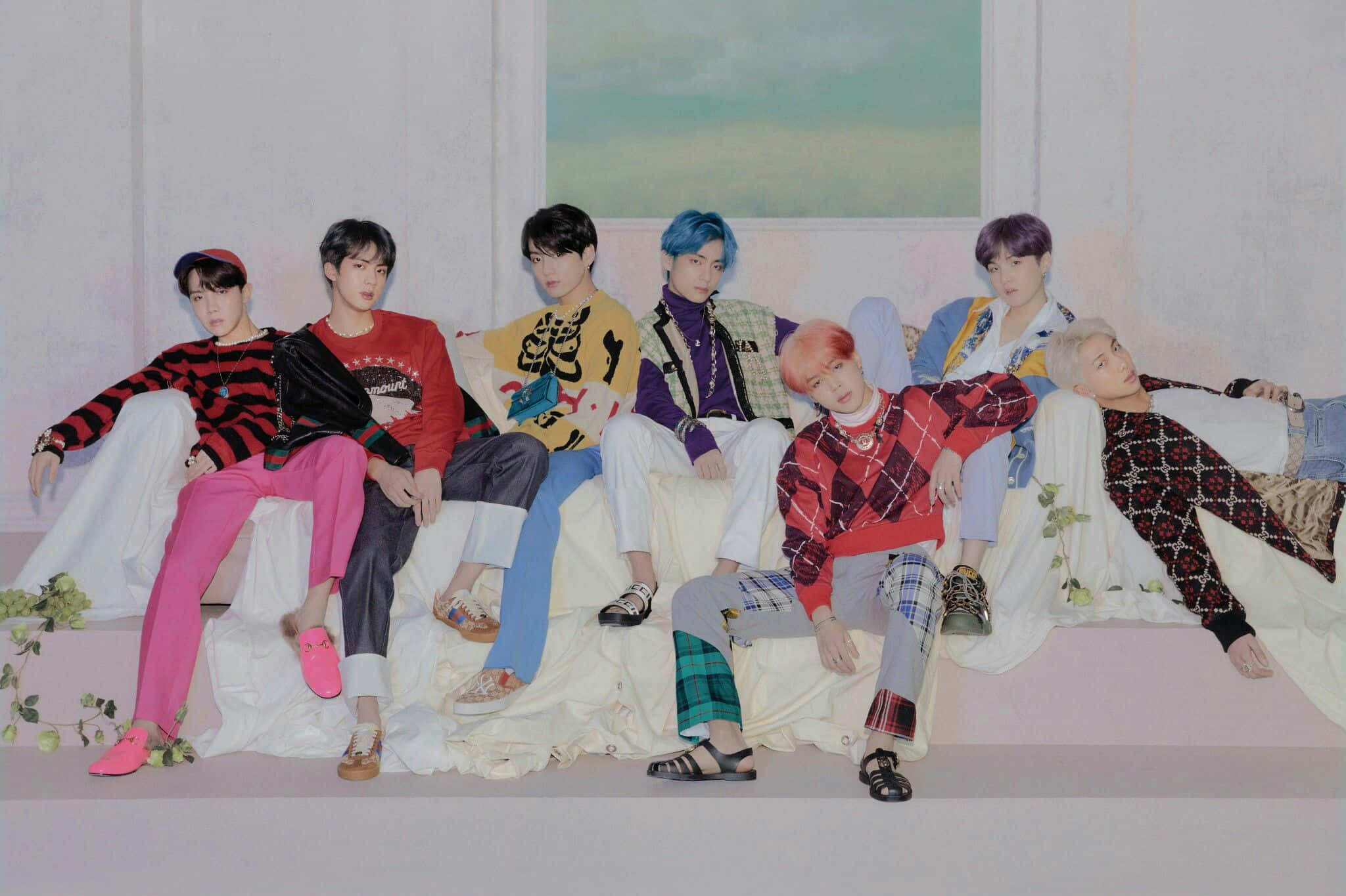 Big Hit Entertainment 桌布 壁紙 — 七位時尚年輕男子身穿色彩繽紛的服裝，在白色布藝長椅上悠閒地靠著柔和的粉彩牆壁。
