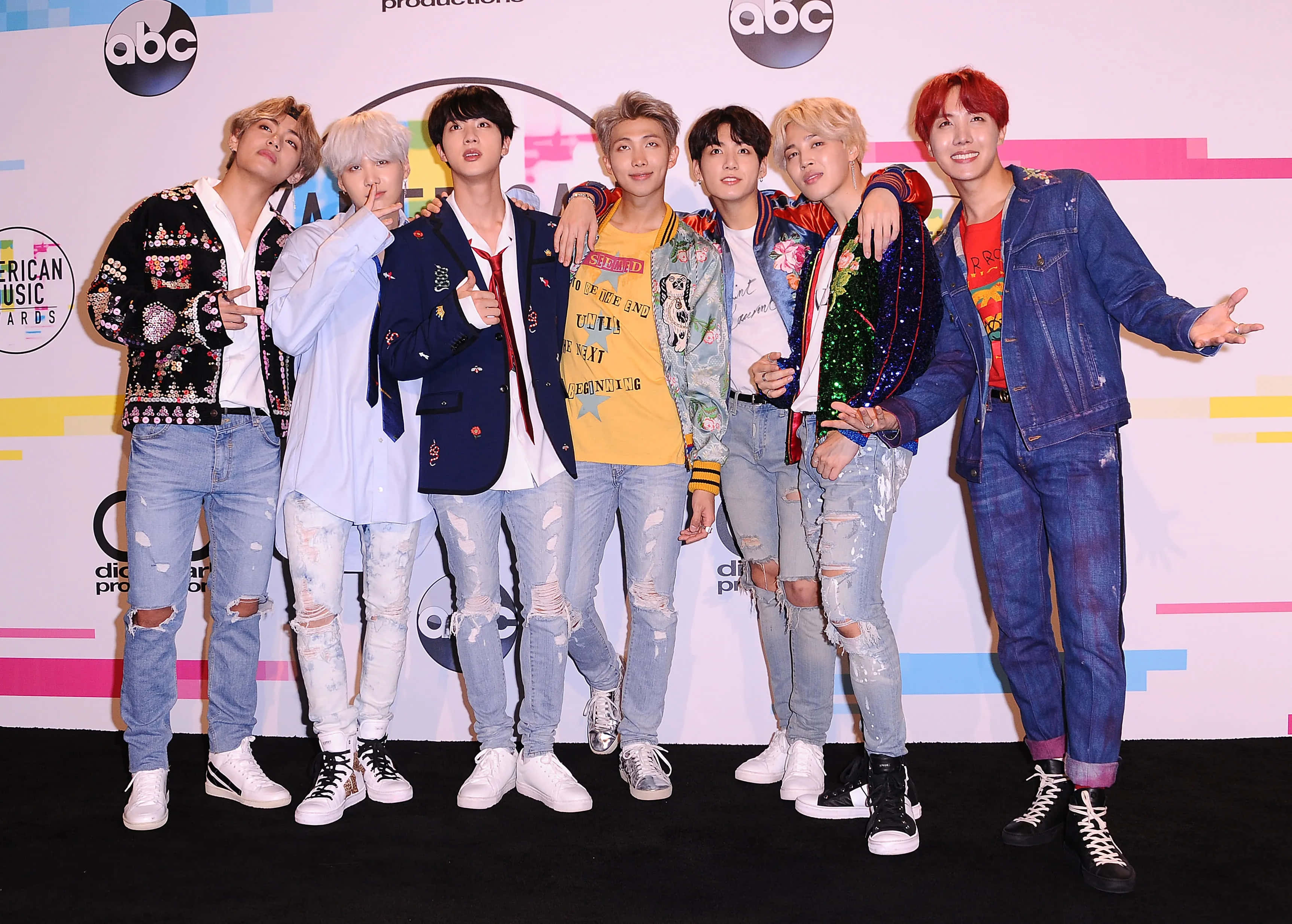 Bts Performance 桌布 壁紙 — 七位時尚的K-pop偶像在頒獎禮的彩色舞台背景前自信地擺姿勢。