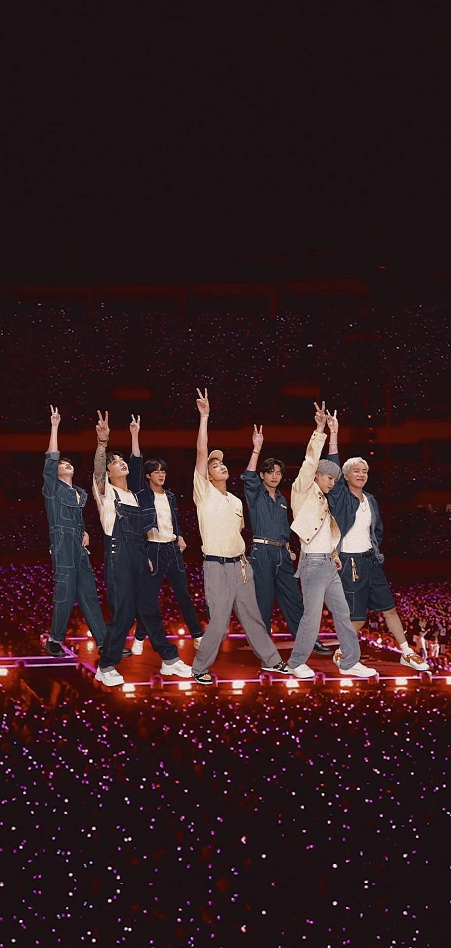 BTS《Permission to Dance》 壁紙 — 七位表演者在燈光璀璨的舞台上向下方人群發出的紫色光芒之海揮舞和平手勢。