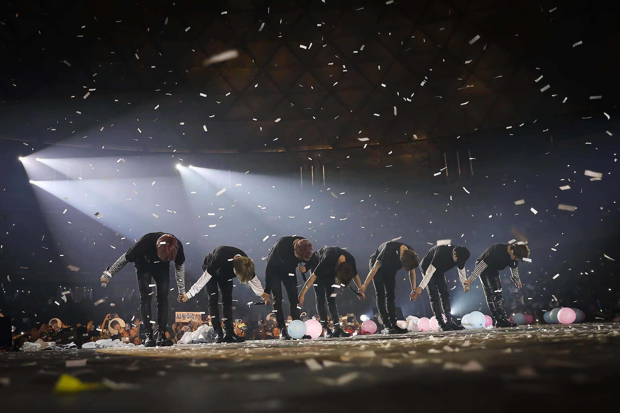 Bts Stage 桌布 壁紙 — 七位表演者在舞台上深深鞠躬，五彩紙屑在明亮的聚光燈下飄落。