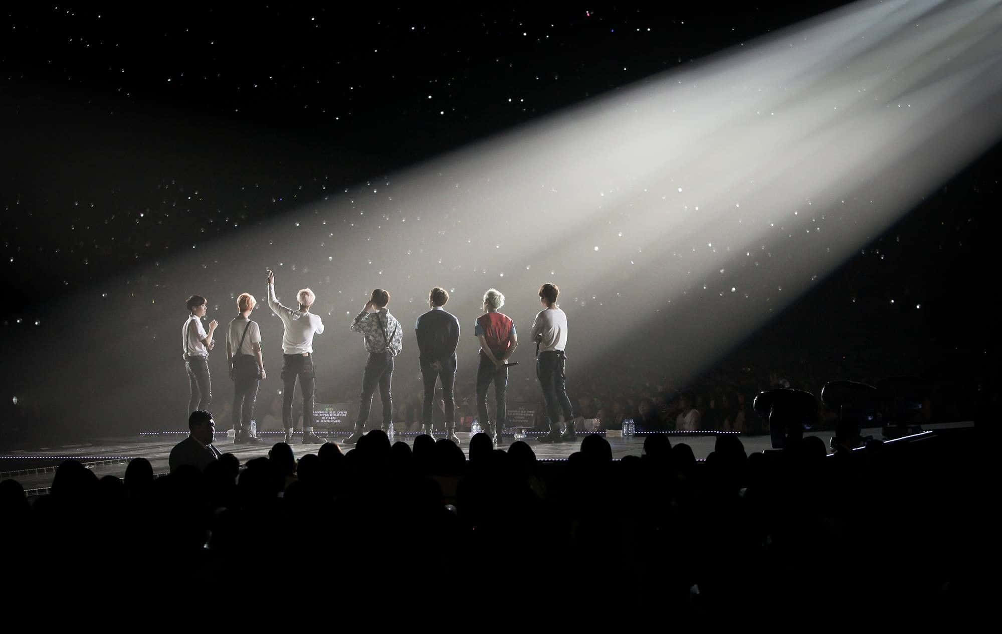 Bts Stage 桌布 壁紙 — 七位表演者站在舞台上的聚光燈下，背景是星空，周圍有五彩紙屑飄落。