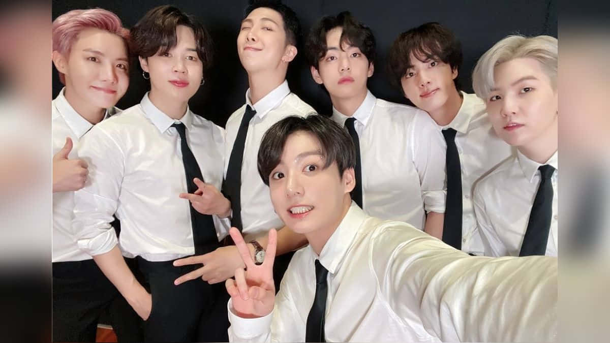 BTS - 壁紙 — 七位身穿白襯衫、打黑色領帶的年輕男子在深色背景前，愉快地擺出各種有趣的手勢自拍。