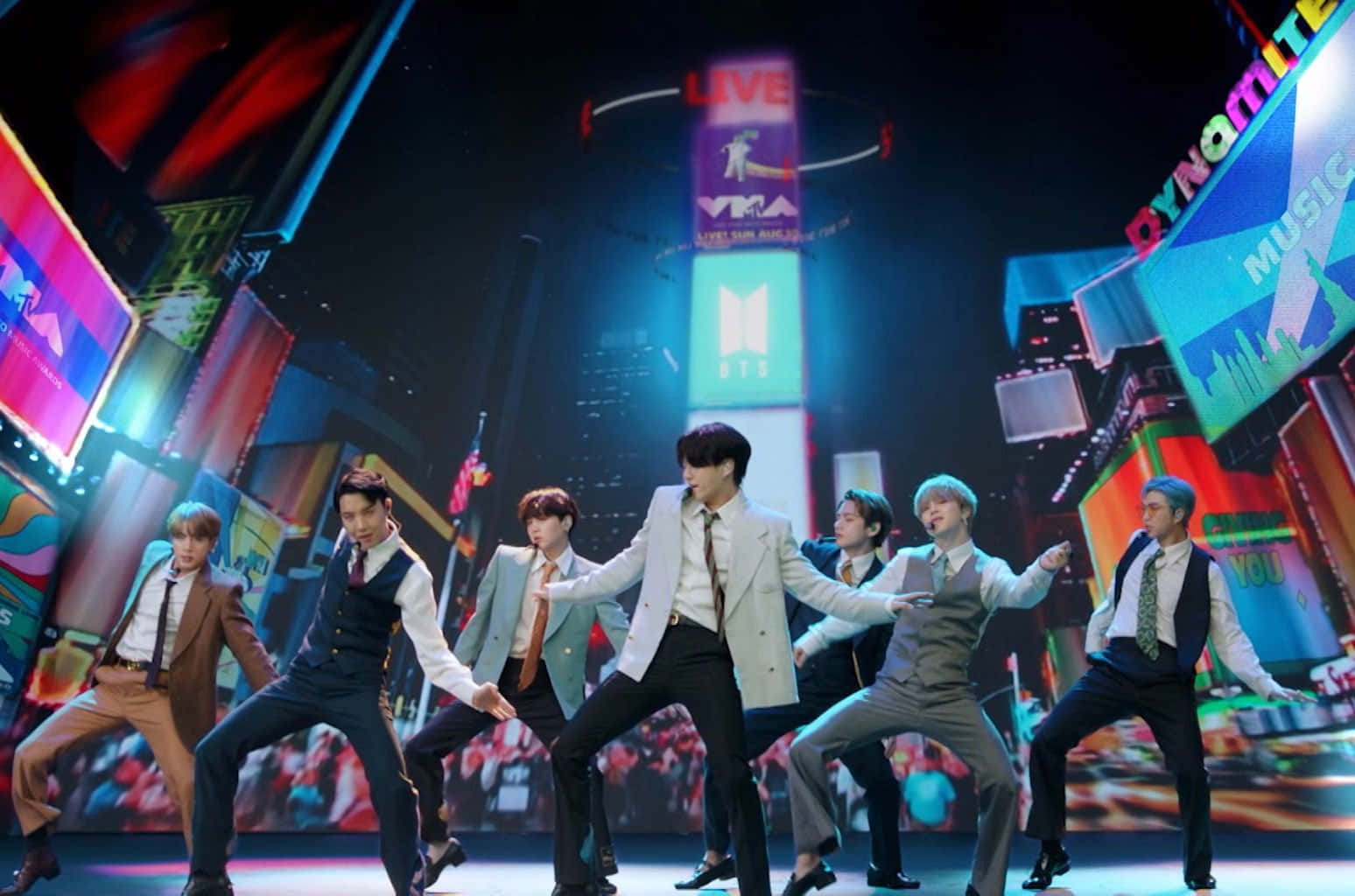 Bts Performance 桌布 壁紙 — 七位身穿西裝的男舞者在霓虹燈照亮城市景觀背景下，配合「Dynamite」和「BTS」標誌擺出同步姿勢。