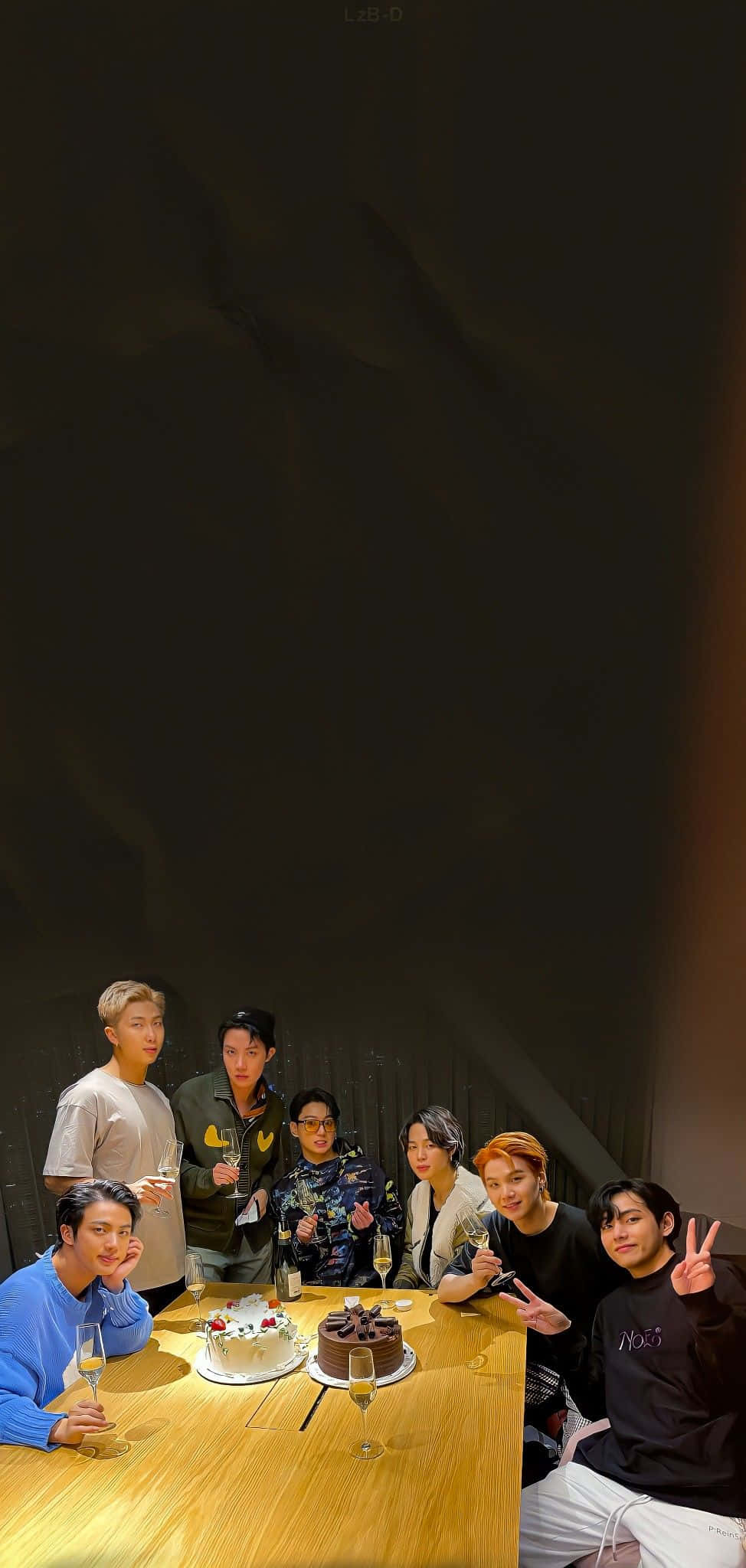 Bangtan Sonyeondan 桌布 壁紙 — 七個年輕男子圍著一張木桌，桌上放著兩個蛋糕和香檳杯，房間燈光昏暗。