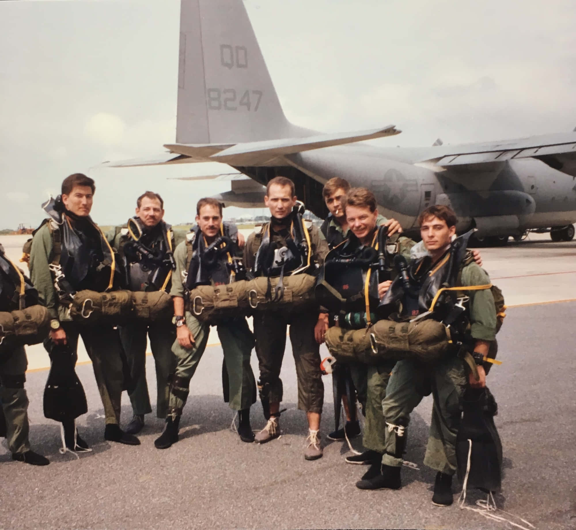 Air Force 桌布 壁紙 — 七名全副武裝的軍用傘兵在機場停機坪上一架大型灰色運輸機前自信地擺姿勢。