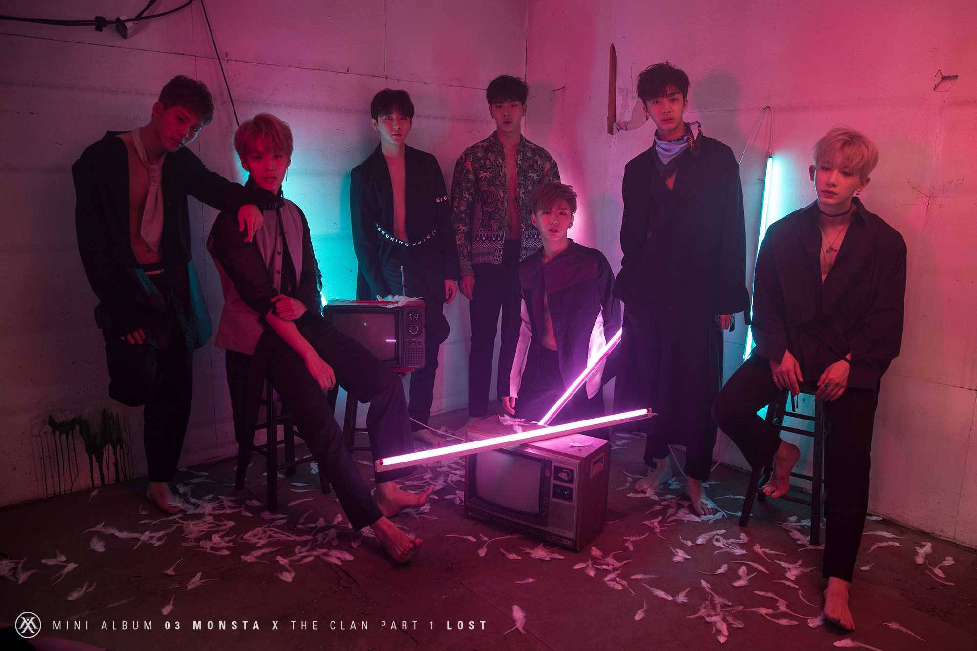 Monsta X The Clan 壁紙 — 七名身穿深色服裝的男子在一個充滿霓虹燈、有破損電視和散落羽毛的房間裡戲劇性地擺姿勢。