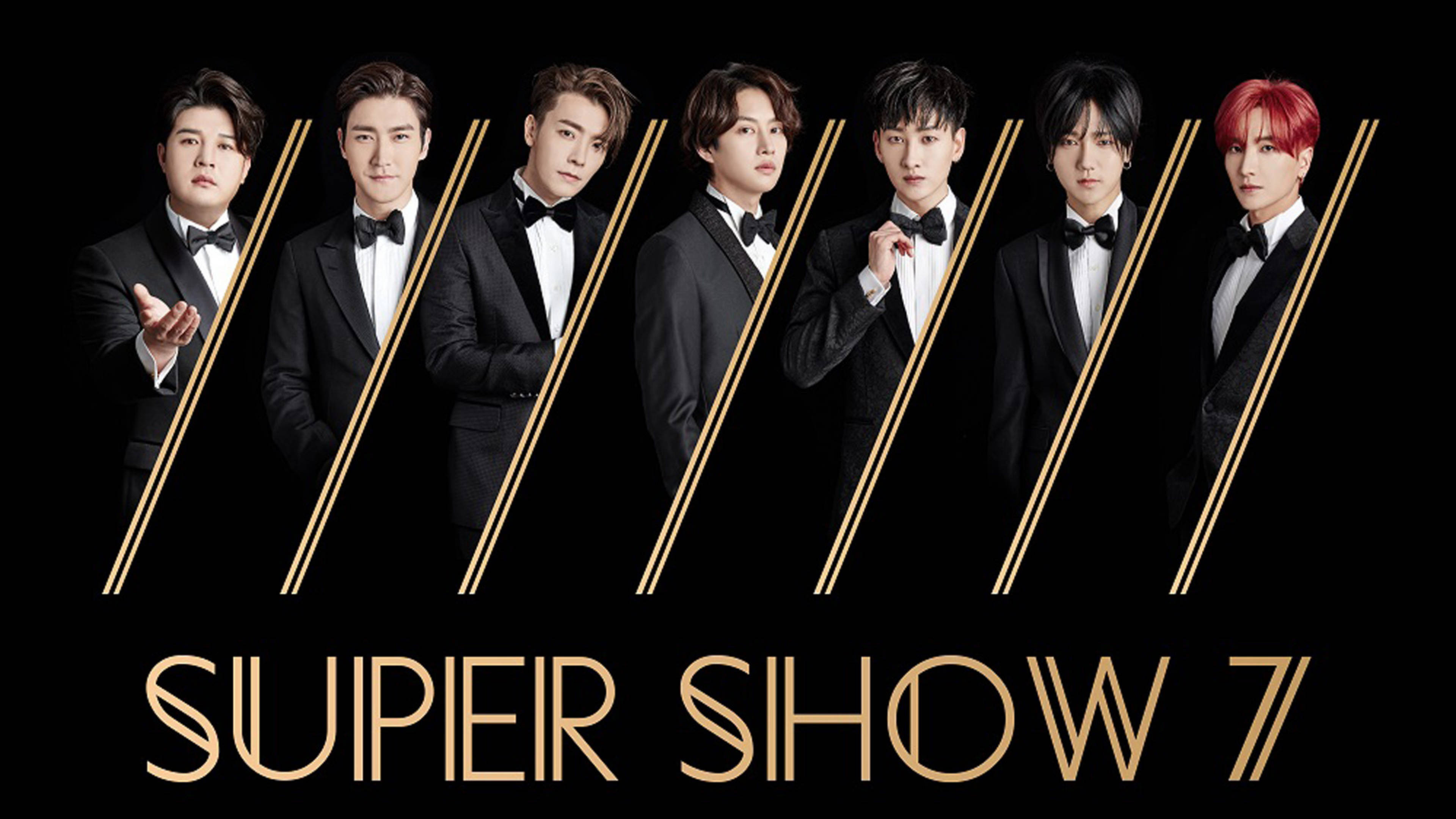 Super Junior Super Show 7 壁紙 — 七名身穿黑色燕尾服、佩戴領結的男士站在帶有金色對角線和文字的黑色背景前。