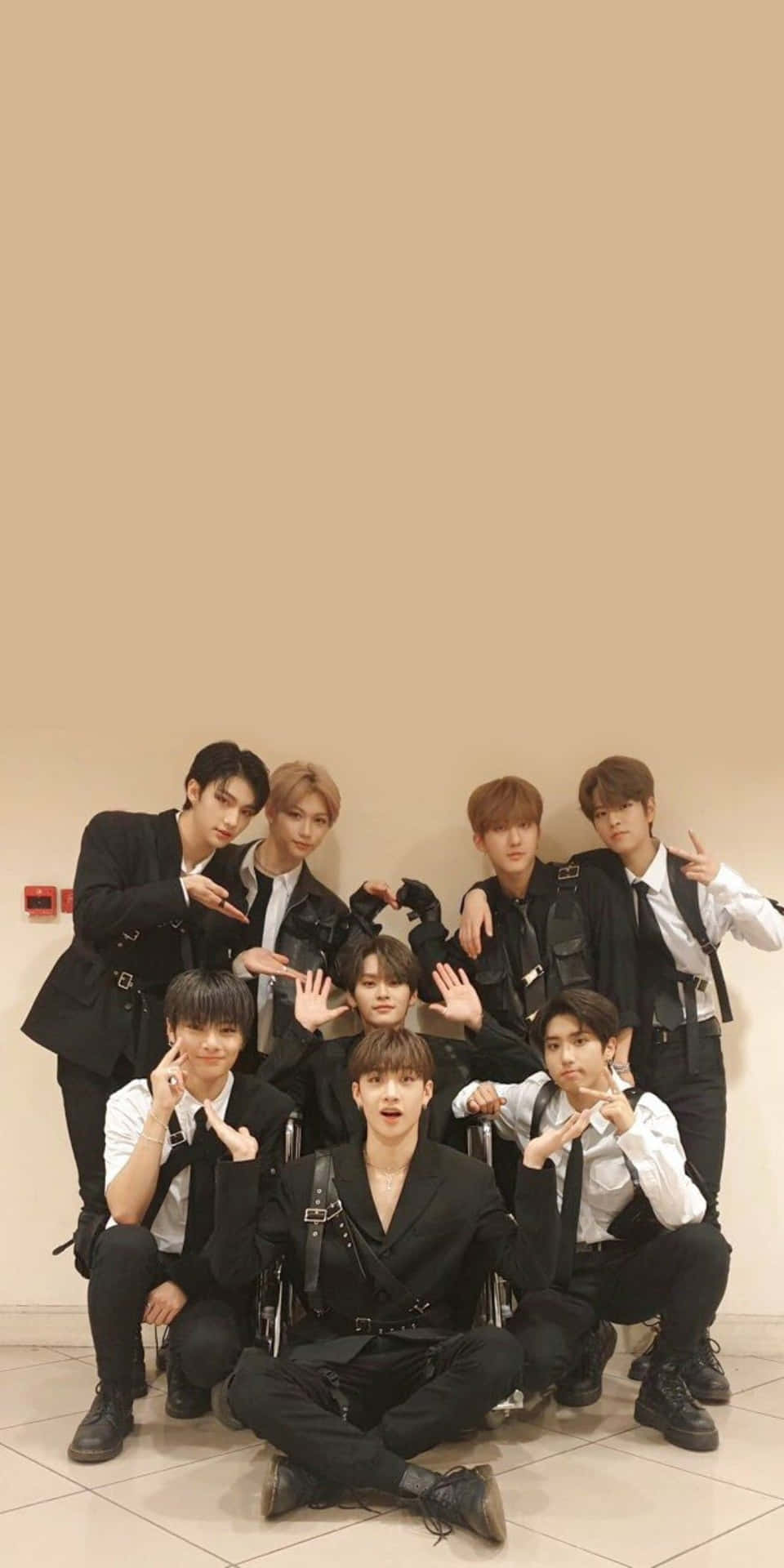 七名身穿黑色西裝的年輕男子在室內以俏皮的手勢擺姿勢。 — Stray kids GIF 壁紙
