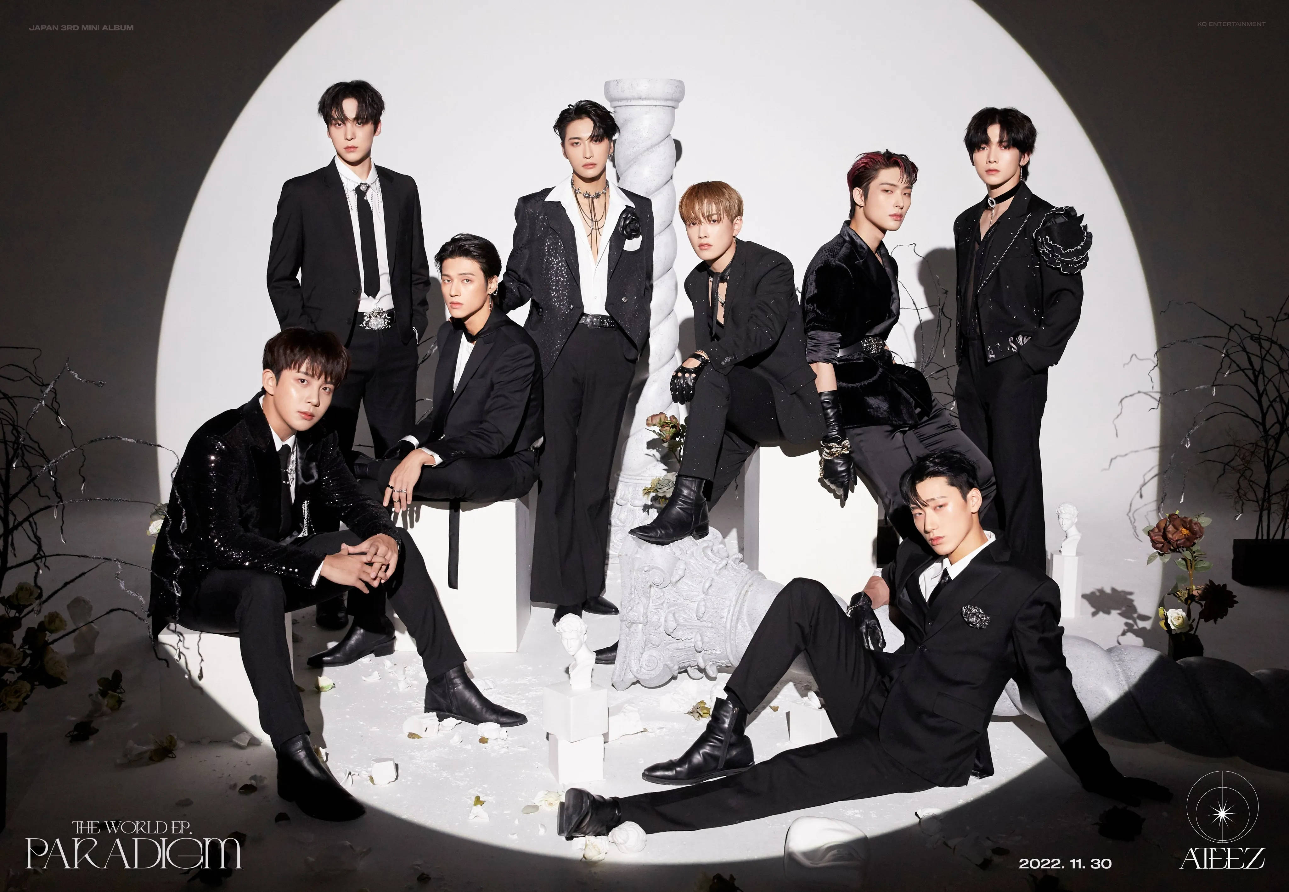 ateez 桌布 壁紙 — 七名身穿黑色西裝的男子在一個圓形白色拱門內戲劇性地擺姿勢，拱門上裝飾著散落的白色花朵和光禿的樹枝。