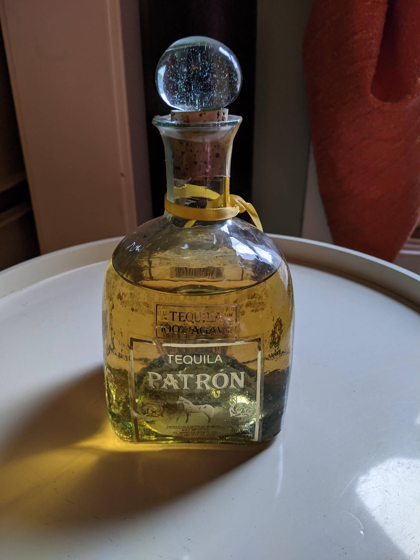 陽光下白色托盤上帶有水晶塞的Patron龍舌蘭酒瓶。
