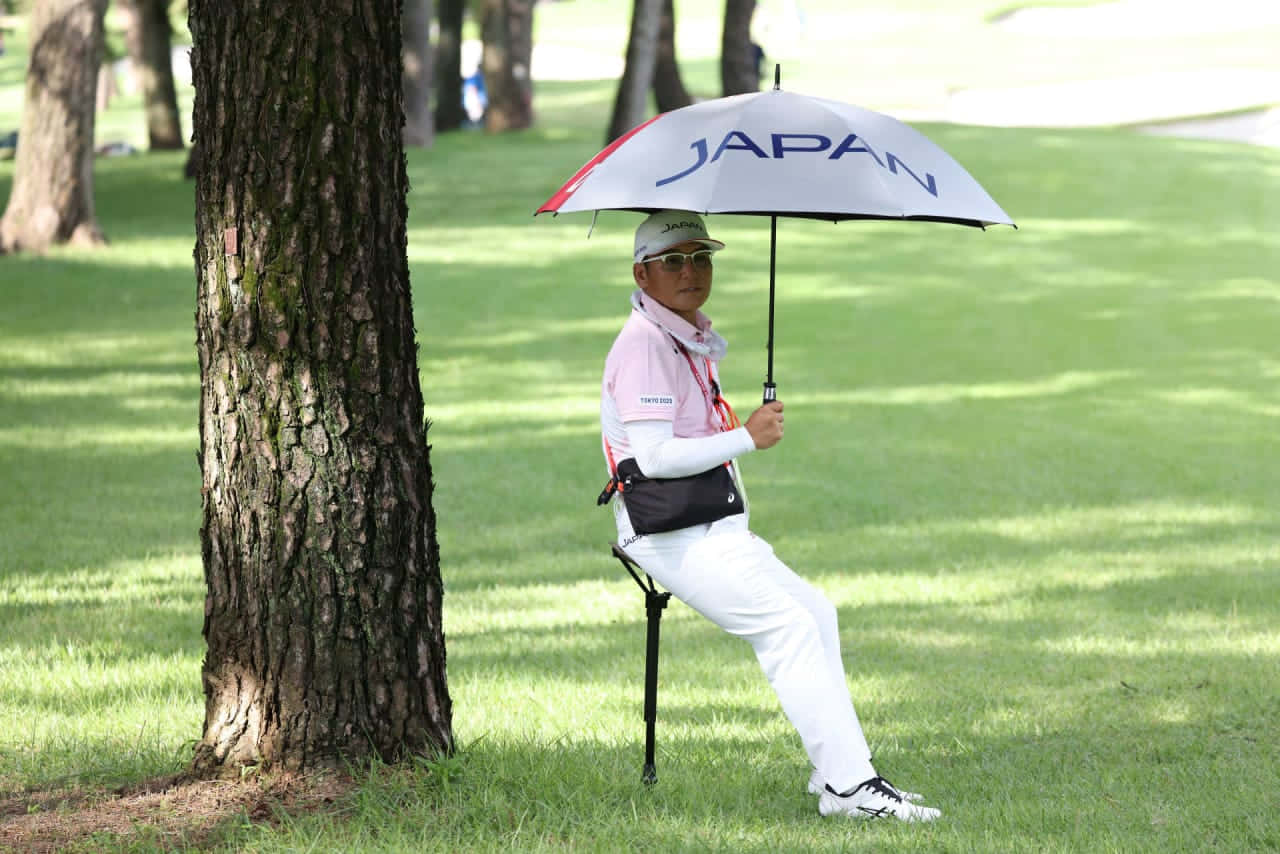 高爾夫球手在高爾夫球場的樹旁，在Japan雨傘下休息。