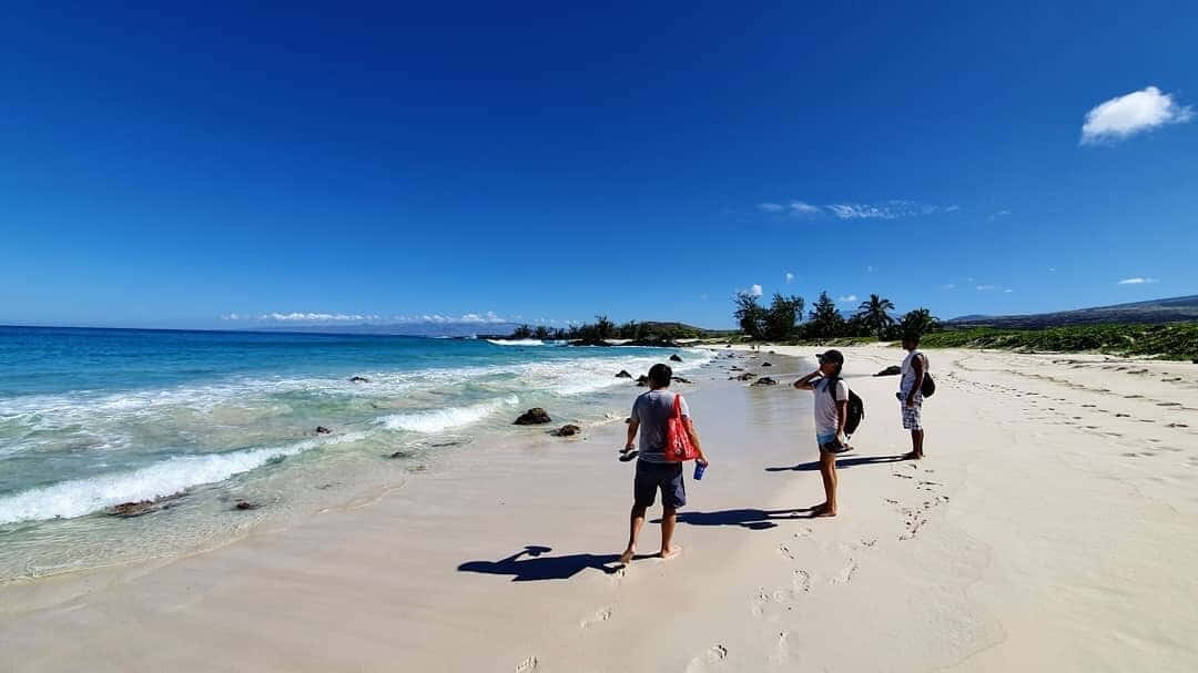 Hawaiian Island 桌布 壁紙 — 三人在陽光明媚的白色沙灘上漫步，碧綠的海浪在清澈的藍天下拍打。