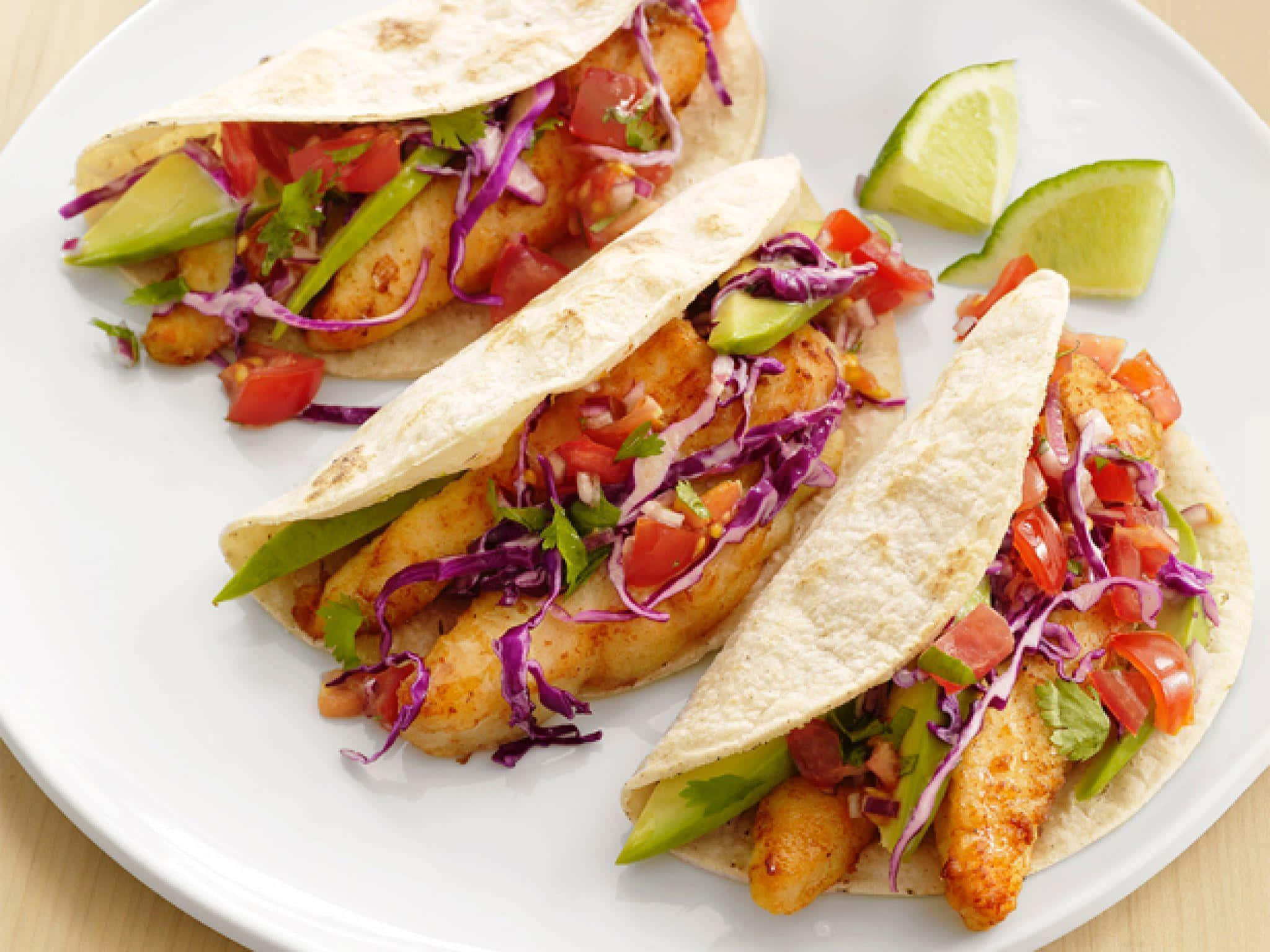 Taco 桌布 壁紙 — 三件香脆魚肉墨西哥卷放在白色碟上，配上鮮艷紫椰菜、番茄、牛油果和青檸角。