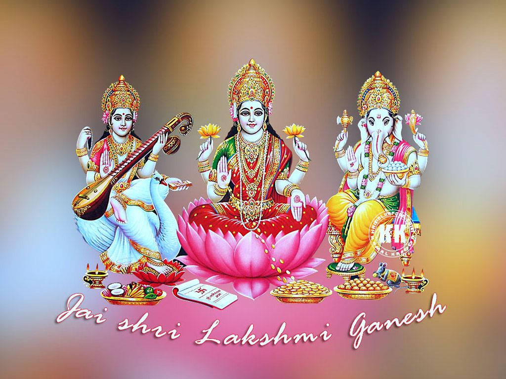 Hindu God 桌布 壁紙 — 三位印度教神祇 Lakshmi、Saraswati 和 Ganesha 身著金色和色彩繽紛的服飾，端莊地坐在粉紅色蓮花上，周圍有供品和蠟燭。