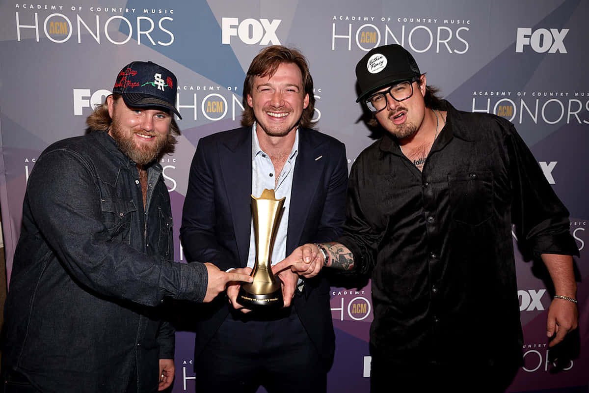 Morgan Wallen 桌布 壁紙 — 三位微笑的鄉村音樂家在ACM Honors活動中一起拿著金色獎盃擺姿勢。