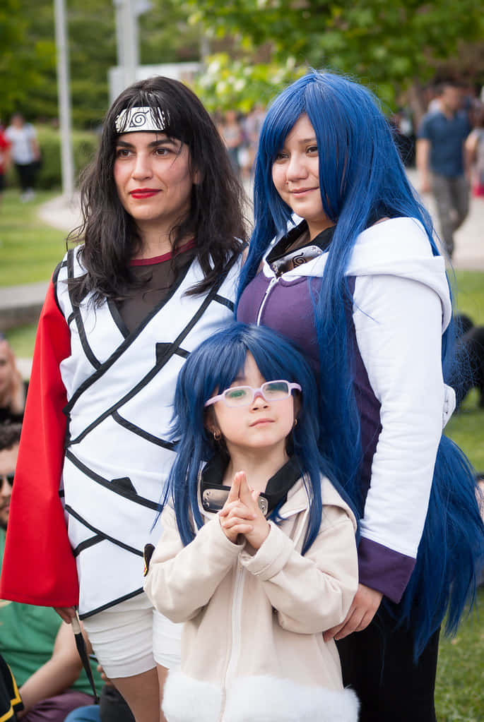Kurenai Yuhi 桌布 壁紙 — 三位穿著火影忍者主題服裝的cosplayer在戶外擺姿勢，擁有鮮豔的藍色頭髮和精緻的服裝，在日光下。