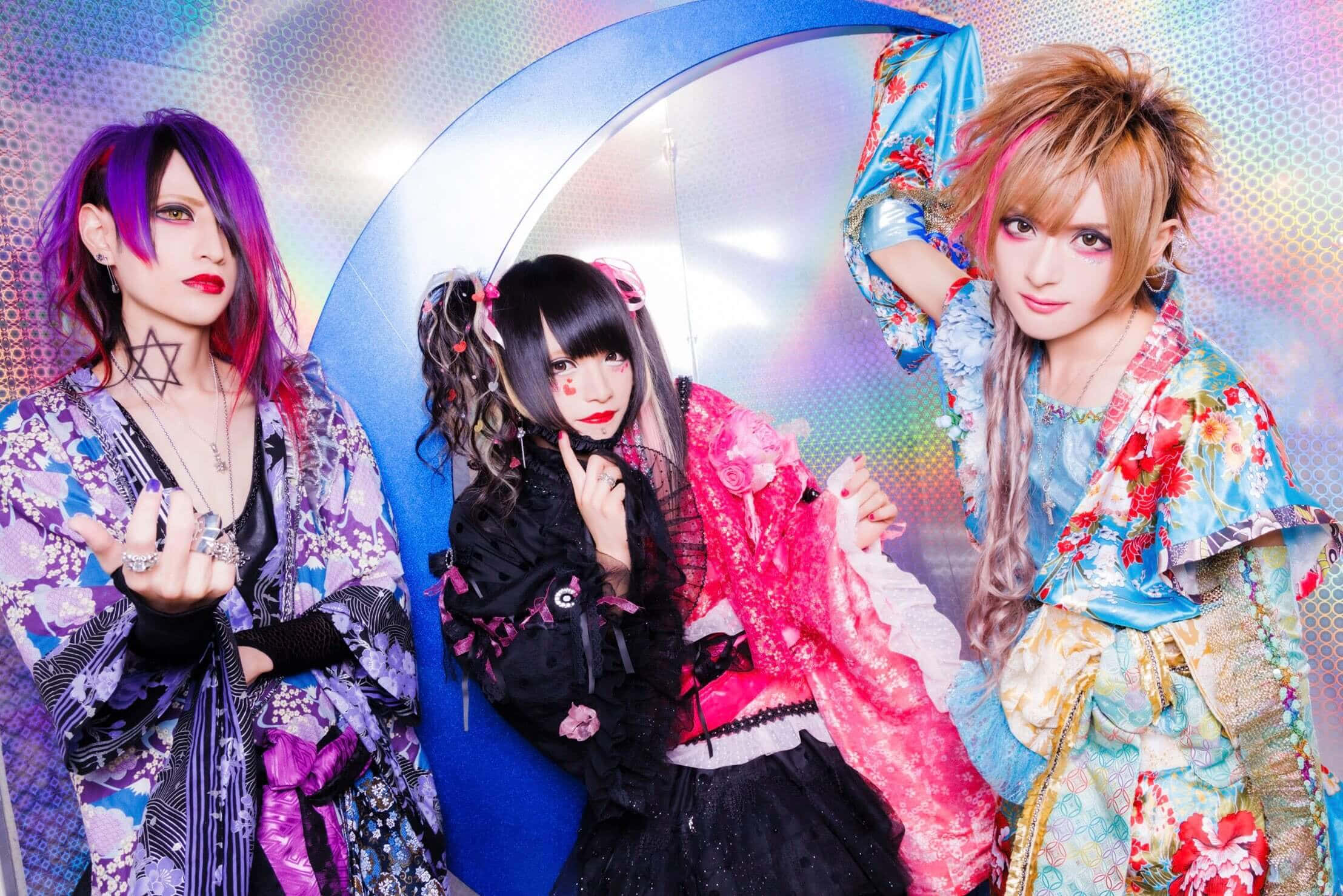 Visual Kei 桌布 壁紙 — 三位穿著鮮豔花卉和服的cosplayer，在閃爍彩虹漸變背景和彎月前戲劇性地擺姿勢。