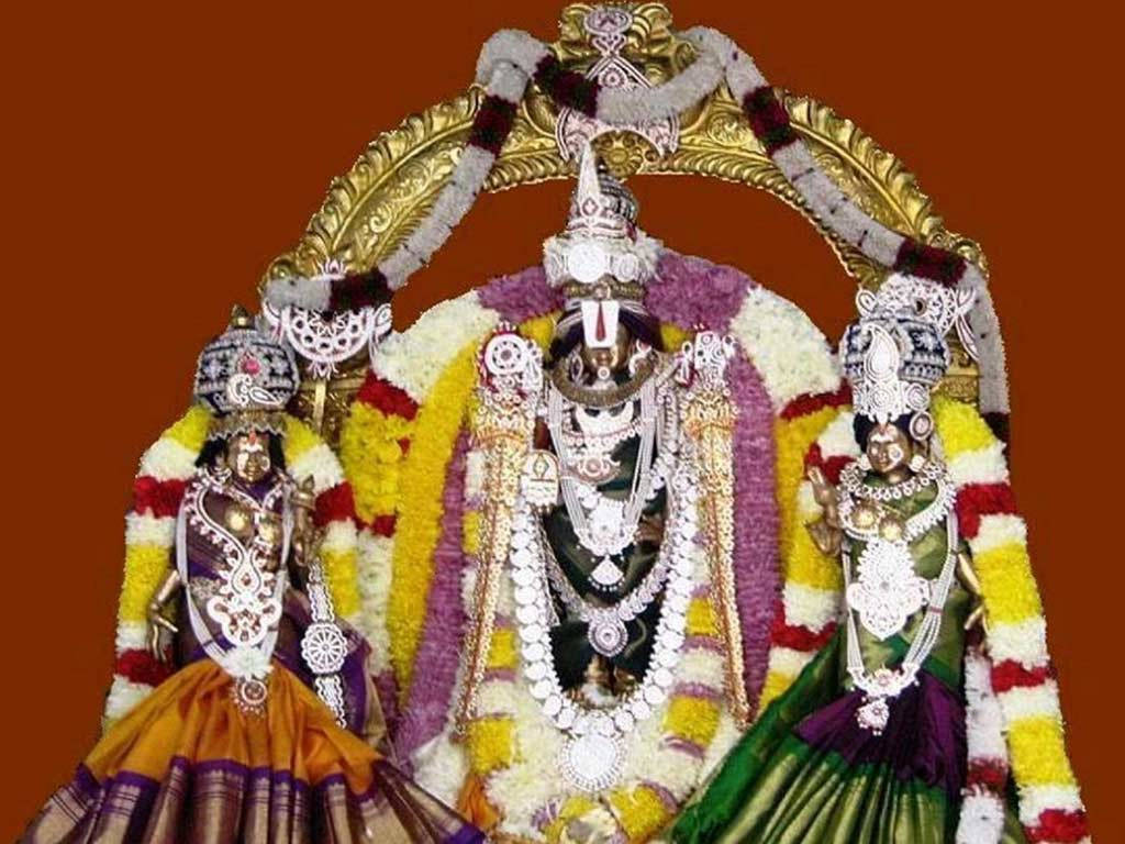 Lakshmi 桌布 壁紙 — 三位華麗的印度教神祇，佩戴金飾和彩色花環，立於金色拱門下，背景為深紅色。