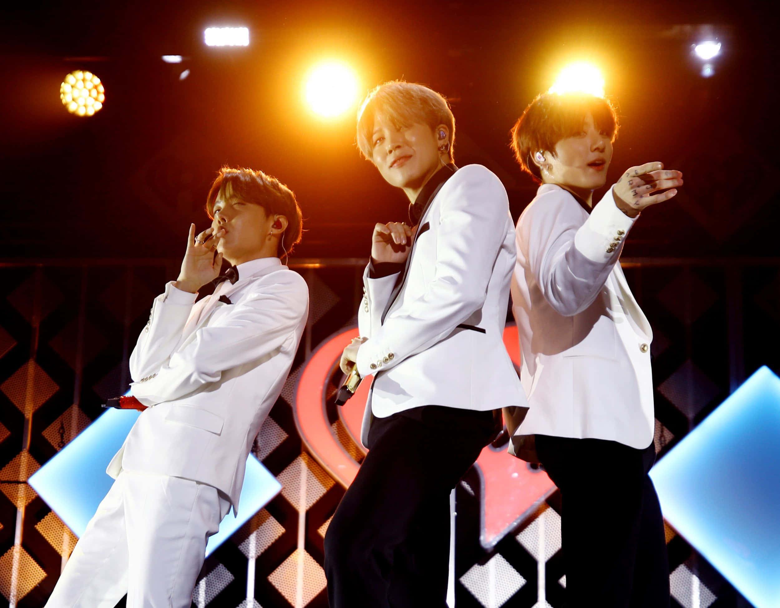 Bts Performance 桌布 壁紙 — 三位身穿白色西裝的男性表演者在明亮的舞台燈光下，以幾何背景擺出動態姿勢。