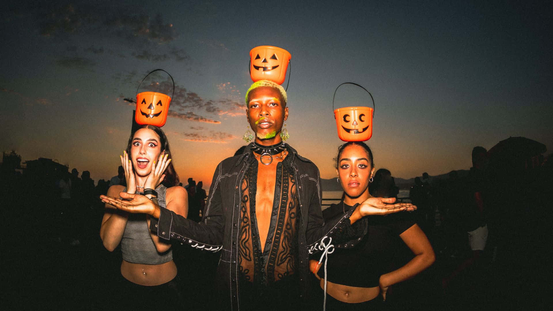 Halloween Costumes 桌布 壁紙 — 三個人喺暮色天空下，將南瓜燈籠桶平衡喺頭上擺甫士。