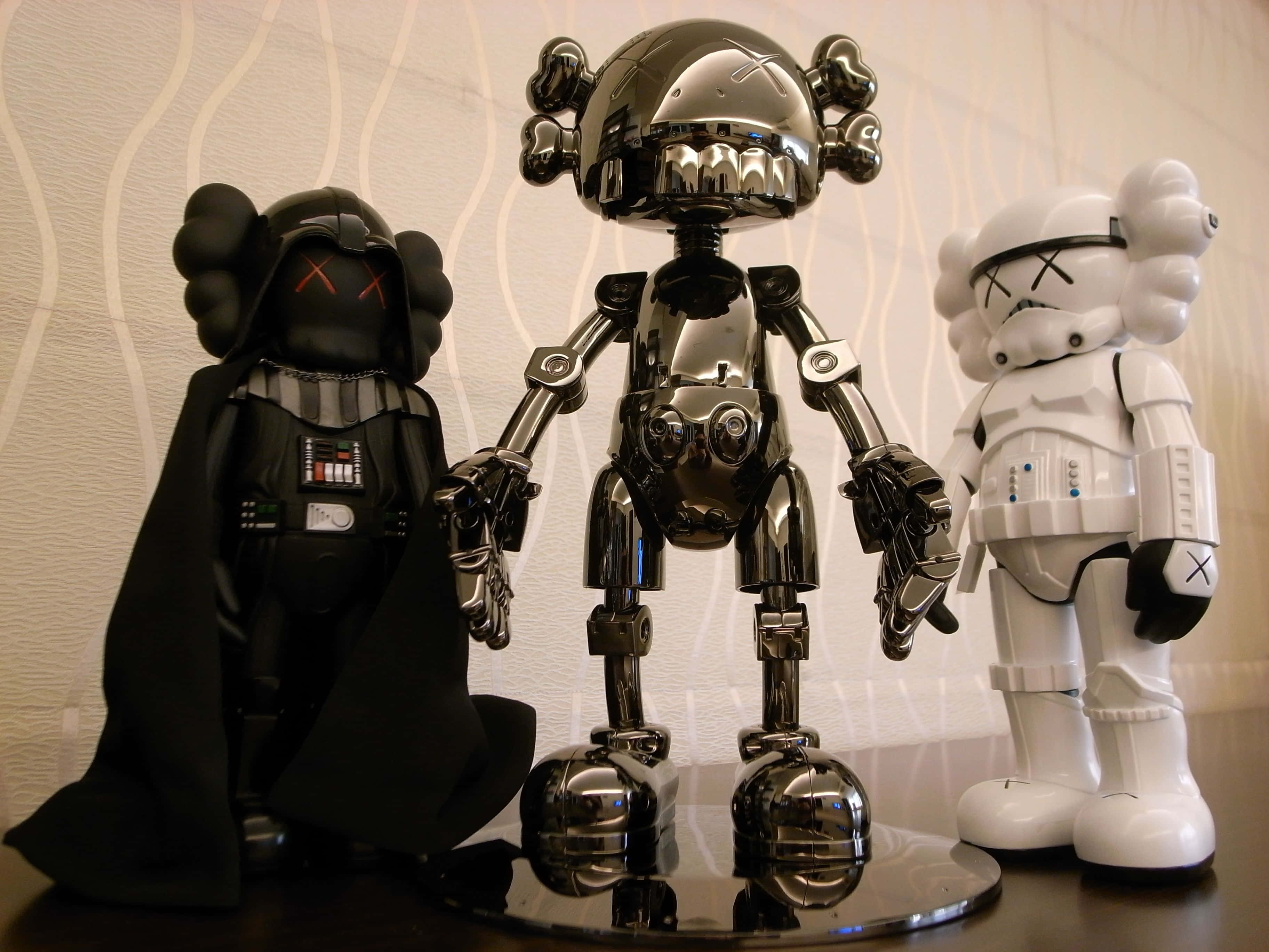 Kaws Stormtrooper 桌布 壁紙 — 三個光面KAWS x Star Wars收藏級人偶：黑武士、風暴兵及鉻機械人，立於反光底座上，背景為波浪紋牆紙。