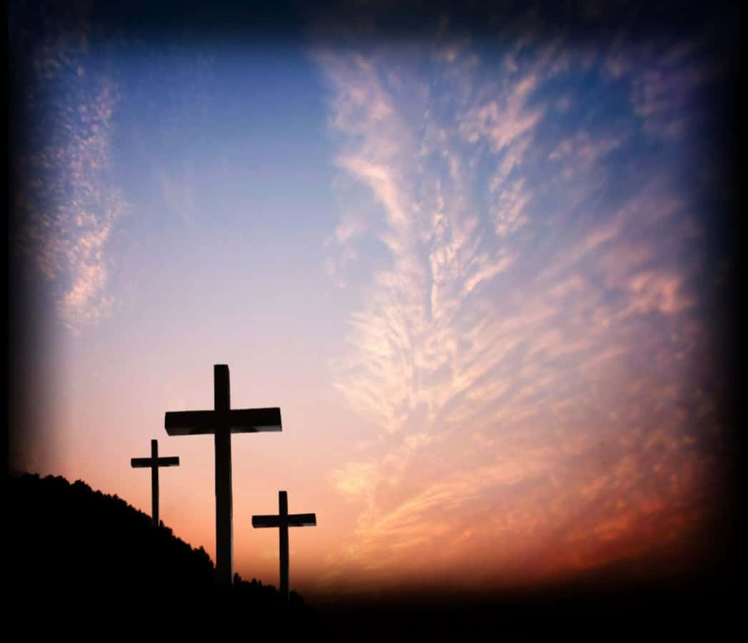 Cool Cross 桌布 壁紙 — 三個剪影十字架矗立在山頂上，以帶有條紋雲彩的戲劇性日落天空為背景。