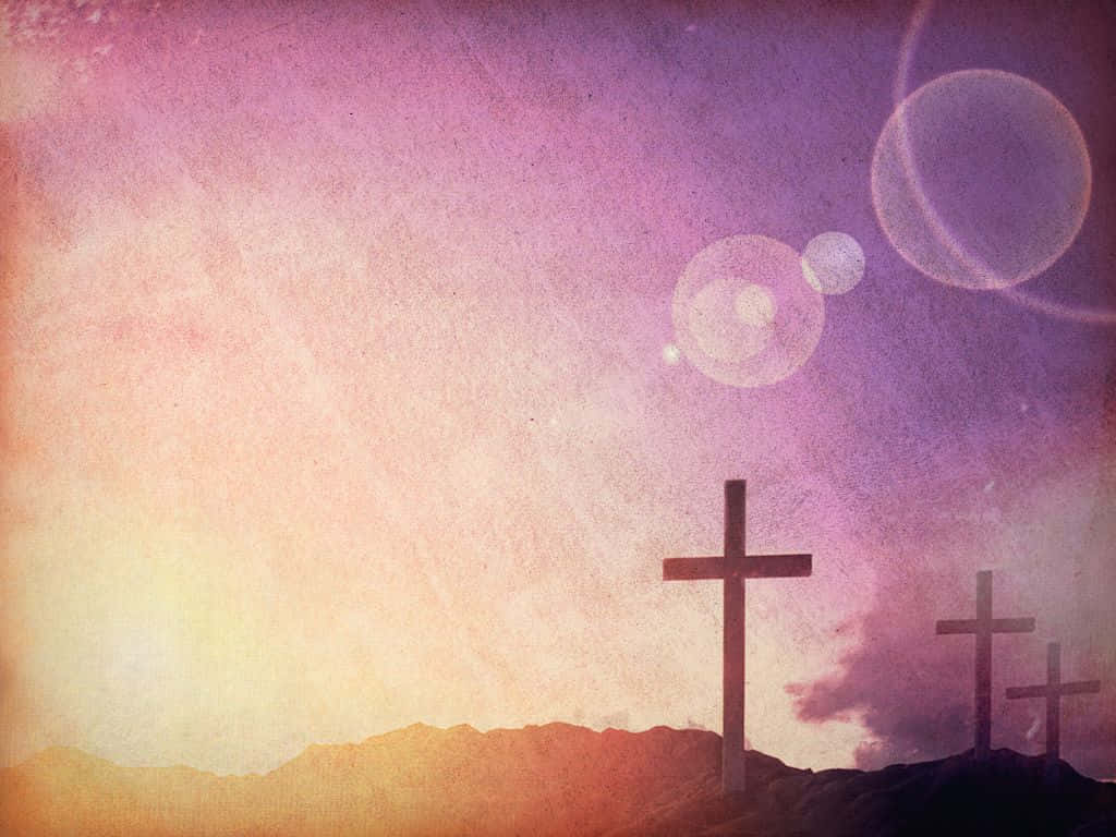 Gospel 桌布 壁紙 — 三個十字架在紋理豐富的紫色和橙色日落天空襯托下，帶有鏡頭光暈，以剪影形式矗立在山丘上。