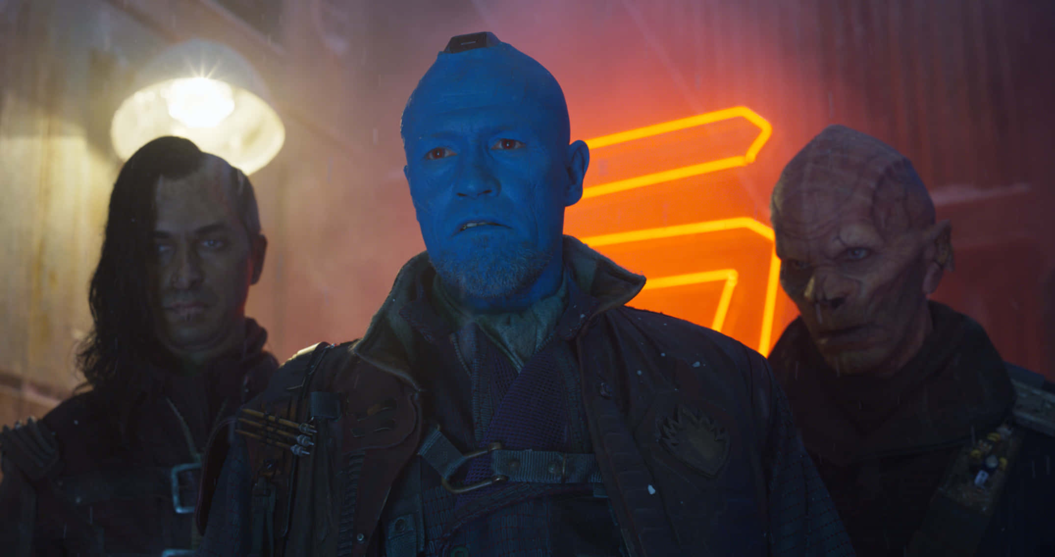 Yondu 桌布 壁紙 — 三個外星人角色站在一條昏暗的未來主義小巷中，被發光的橙色霓虹燈牌照亮。