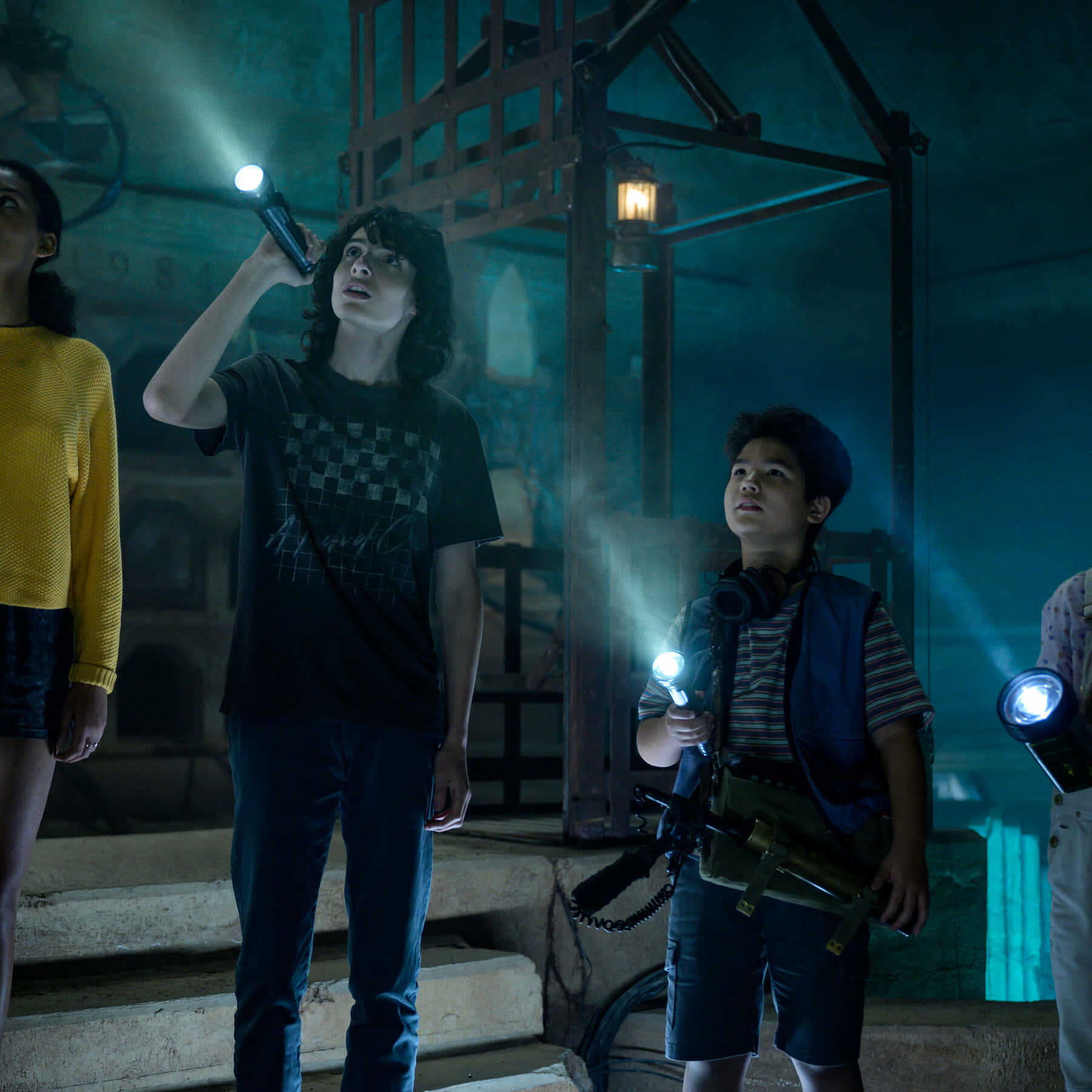 Ghostbusters 桌布 壁紙 — 三個小孩拿著手電筒，在藍綠色光芒下探索昏暗詭異的工業廢墟。