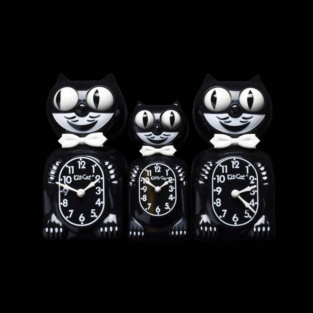 Clock 桌布 壁紙 — 三個帶有白色蝴蝶結和大眼睛的光澤黑色貓形時鐘，立在純黑背景上。
