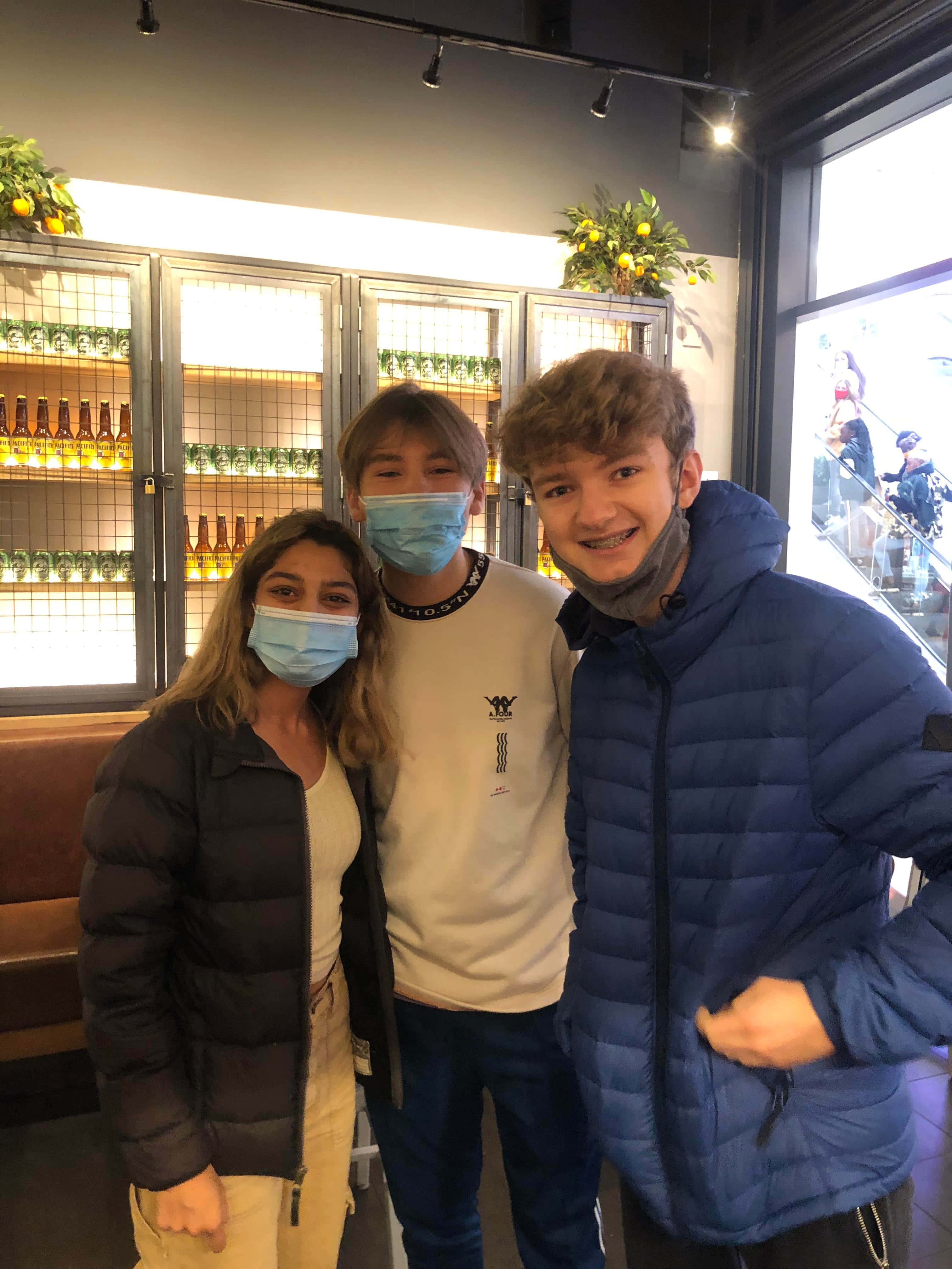 Tommyinnit 桌布 壁紙 — 三個戴著口罩的人喺一間燈光溫暖嘅酒吧入面一齊擺甫士，後面展示咗啤酒樽。
