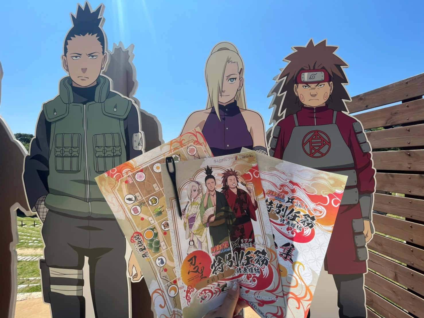 Ino Shika Cho 桌布 壁紙 — 三個火影忍者動畫剪影站在戶外，在晴朗的藍天下手持主題商品。