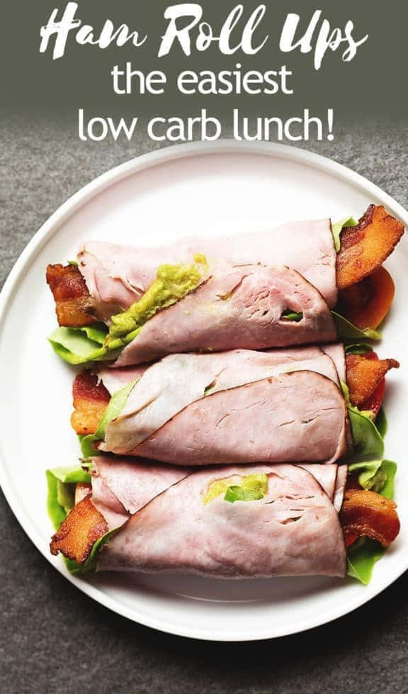 Black Forest Ham 桌布 壁紙 — 三個火腿卷，內有牛油果、煙肉和生菜，整齊地擺放在白色碟子上。