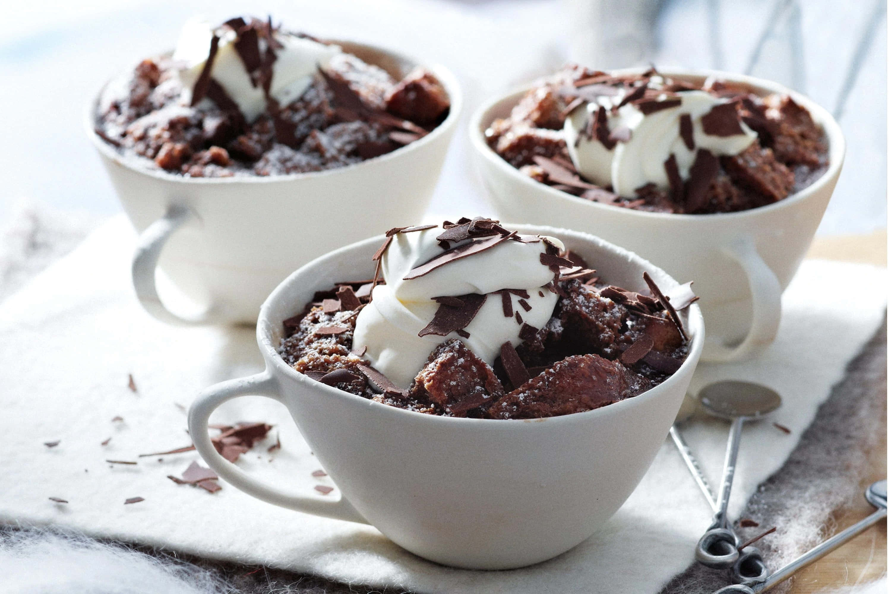 Winter Desserts 桌布 壁紙 — 三個白色馬克杯裝滿濃郁的朱古力杯蛋糕，上面放有忌廉和朱古力碎。