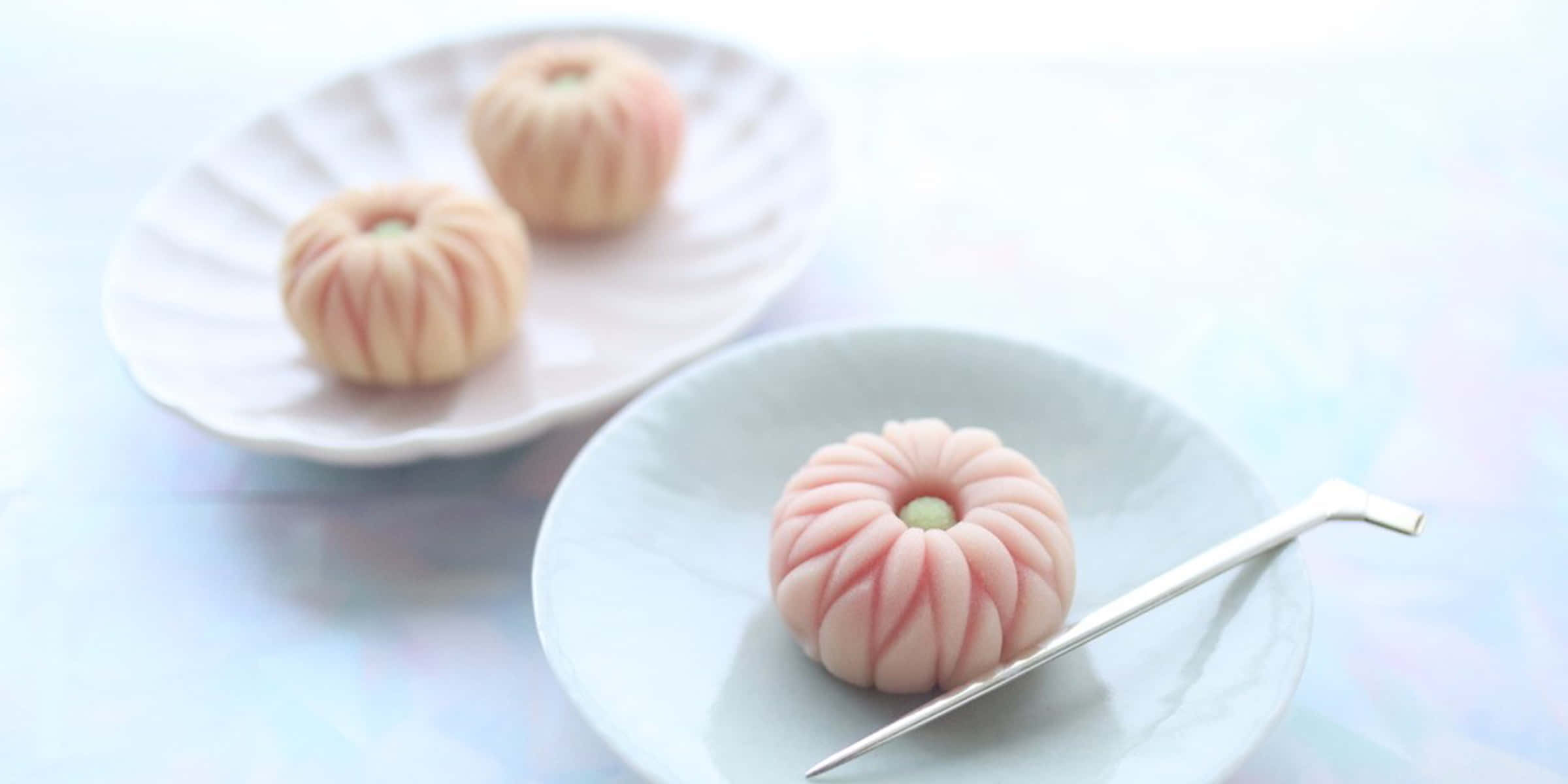 Japanese Sweets 桌布 壁紙 — 三個精緻的粉紅色和白色南瓜形麻糬甜品，優雅地擺放在白色碟子上，配以銀匙。