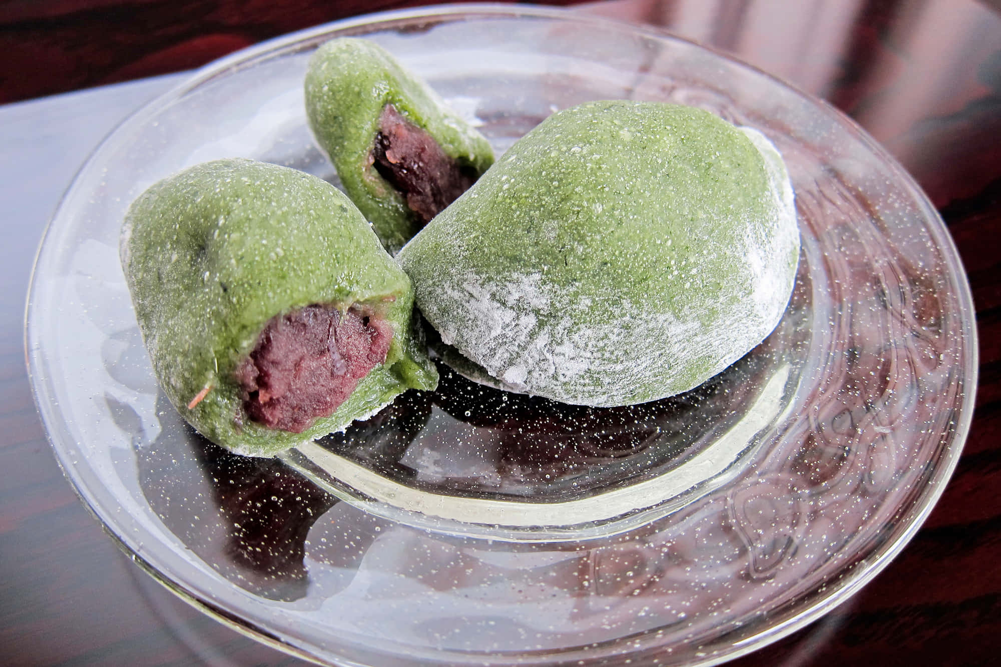 Japanese Sweets 桌布 壁紙 — 三個綠色抹茶麻糬，紅豆餡，撒上糖粉，放在華麗的玻璃碟上。
