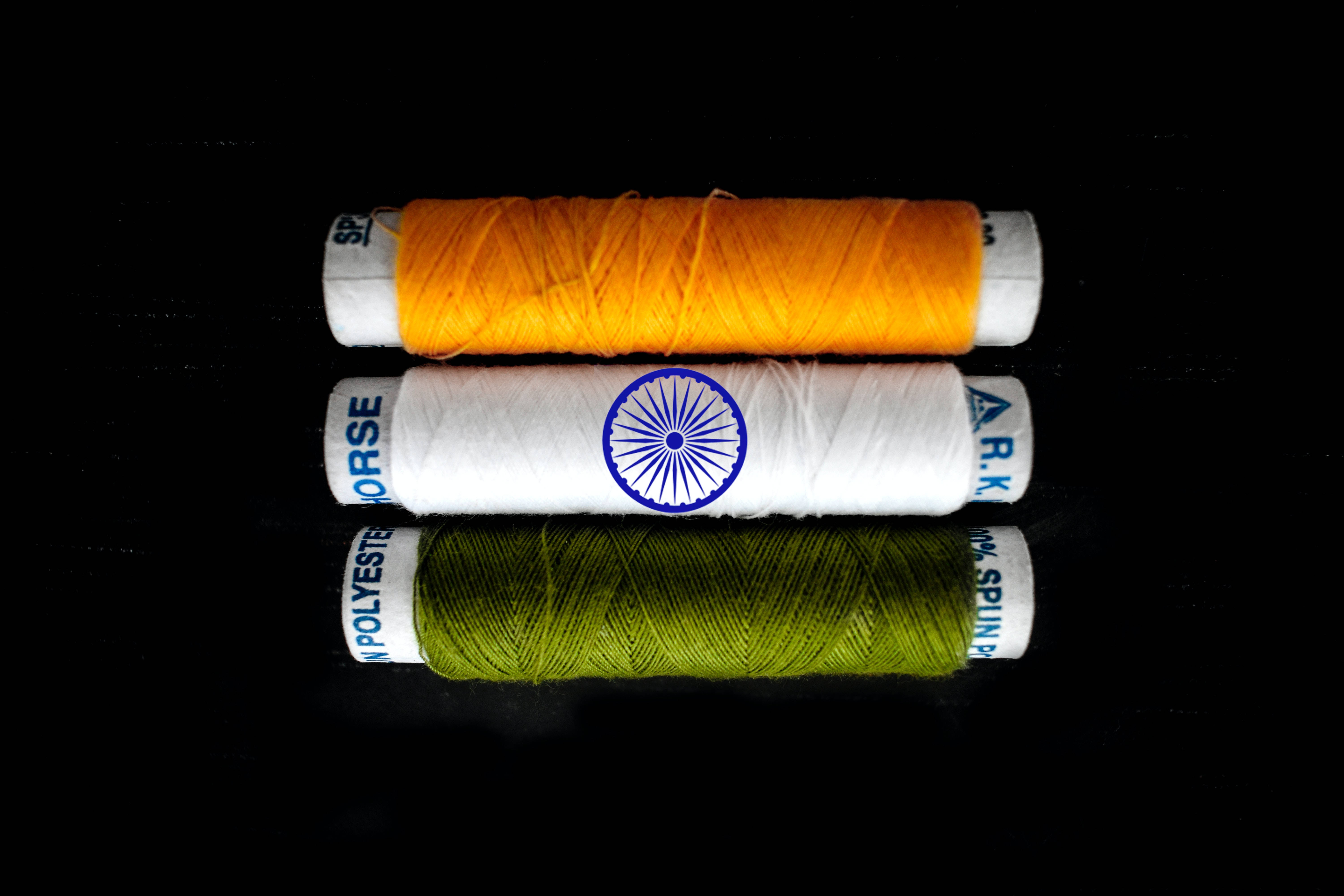 Indian 桌布 壁紙 — 三個線軸，分別為藏紅花、白色和綠色，垂直排列在黑色背景上，白色線軸上有印度國旗標誌。