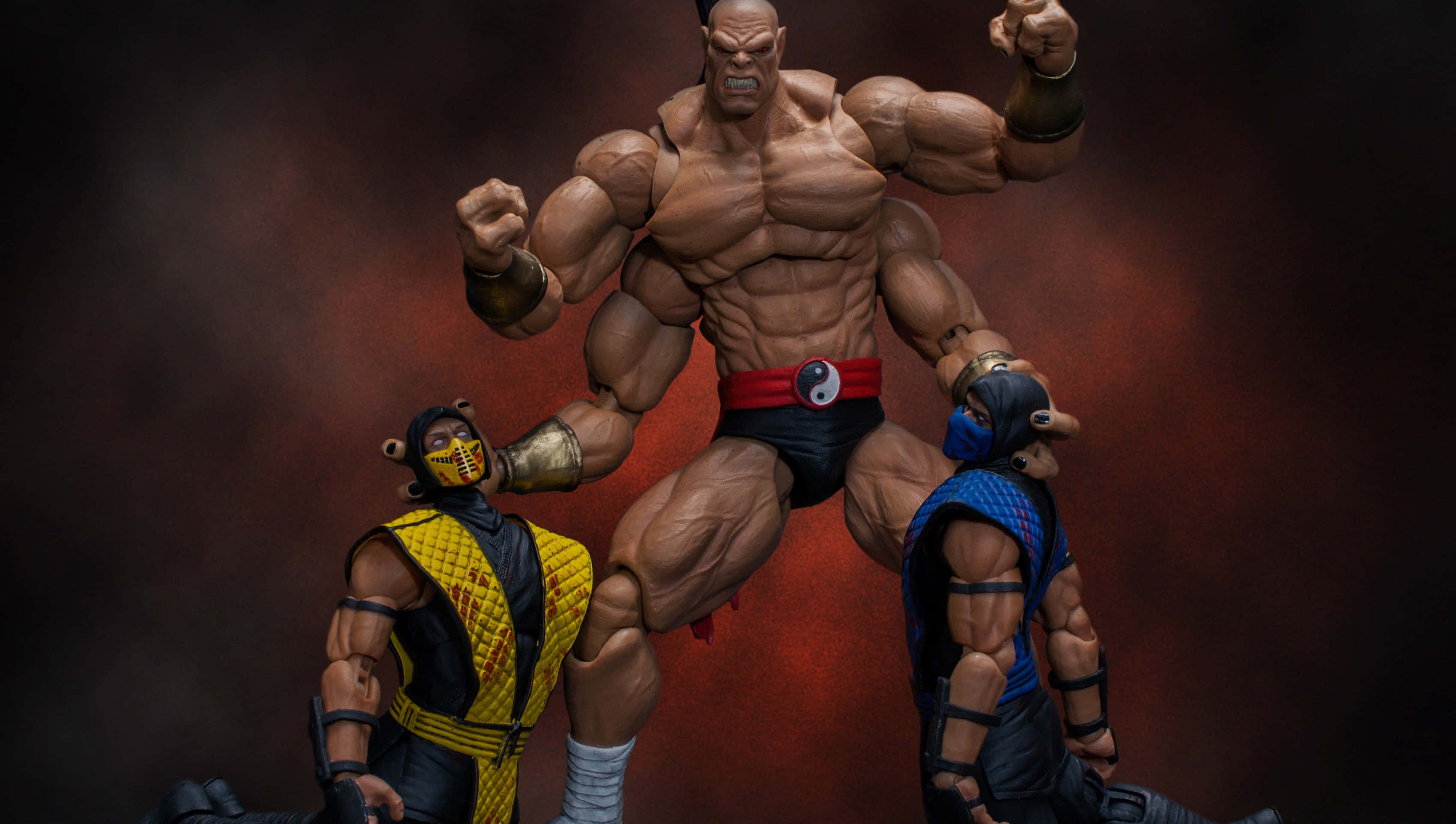 Mortal Kombat Goro 桌布 壁紙 — 三個肌肉發達嘅真人快打動作人偶喺煙霧瀰漫嘅紅色背景下動態擺姿勢。