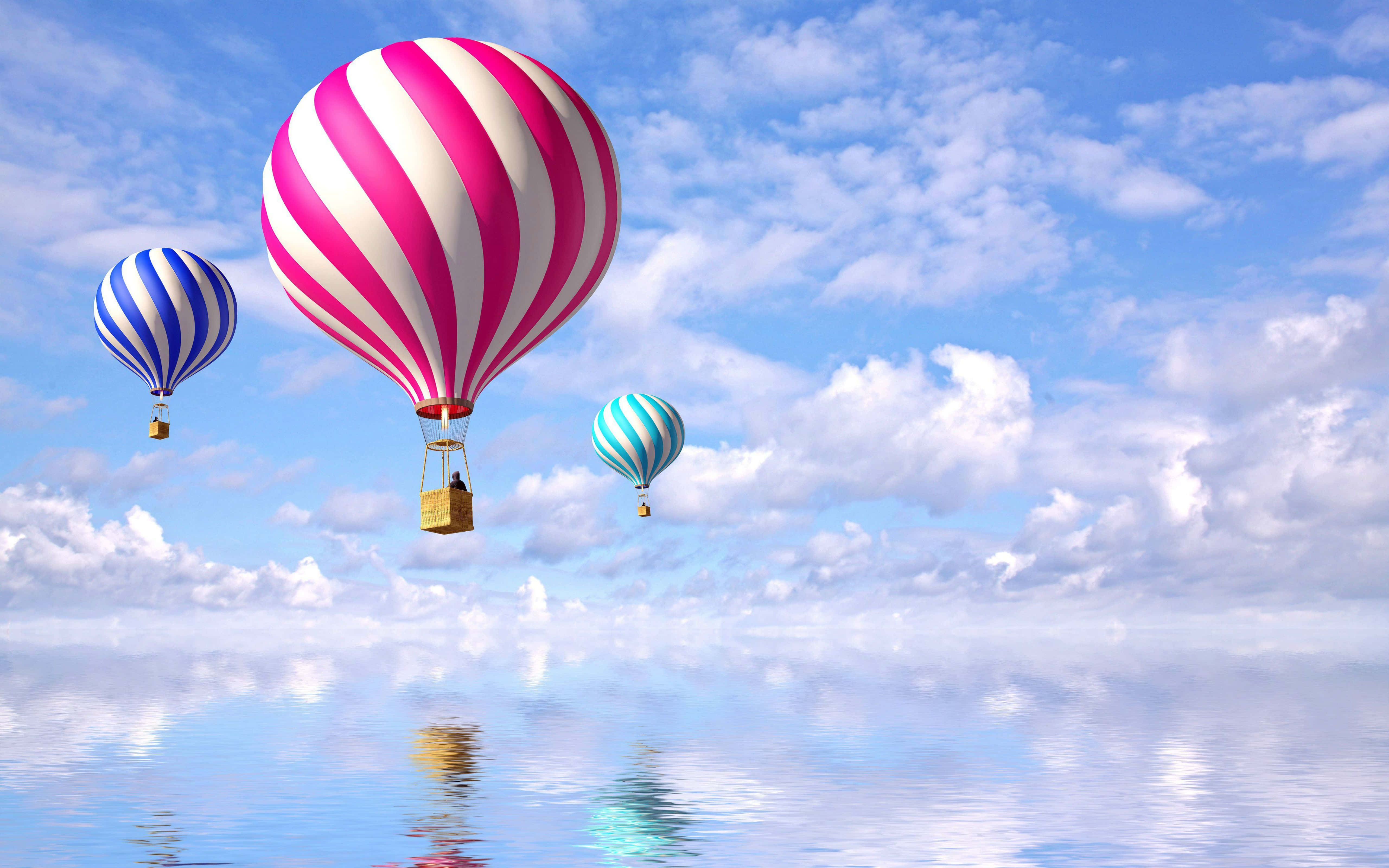Hot Air Balloon 桌布 壁紙 — 三個色彩繽紛的條紋熱氣球漂浮在平靜且反射的水面上，下方是明亮的藍天和蓬鬆的雲朵。