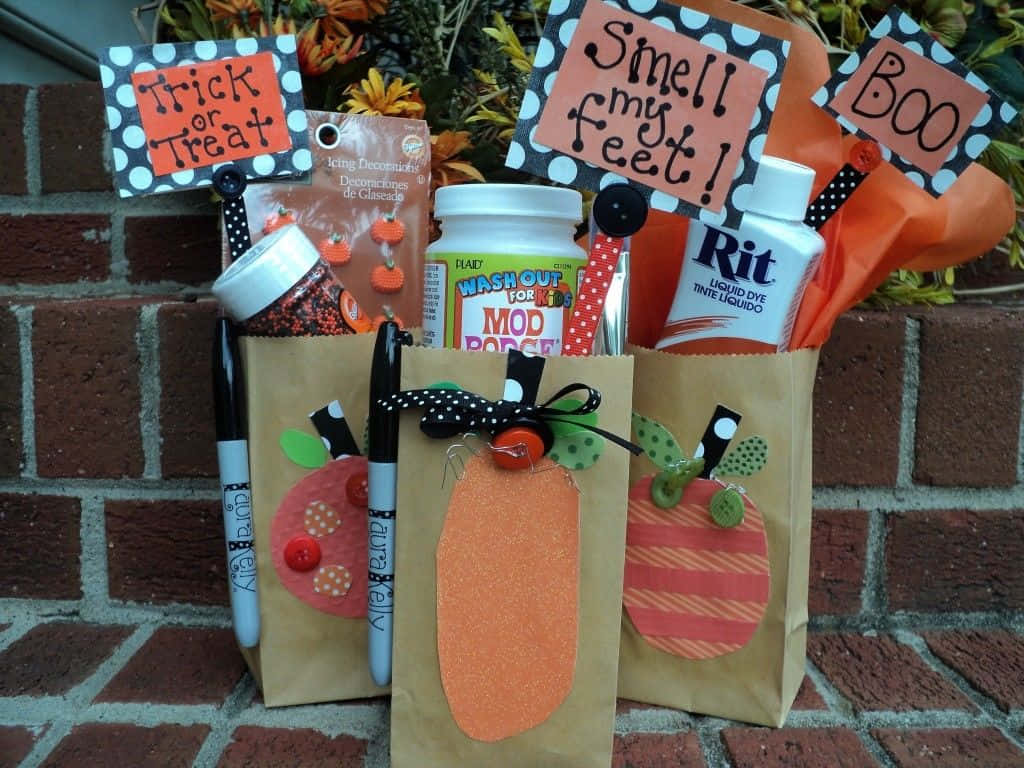 Trick Or Treat Bags 桌布 壁紙 — 三個萬聖節主題手工袋，上面有南瓜和恐怖標誌，靠著磚牆。