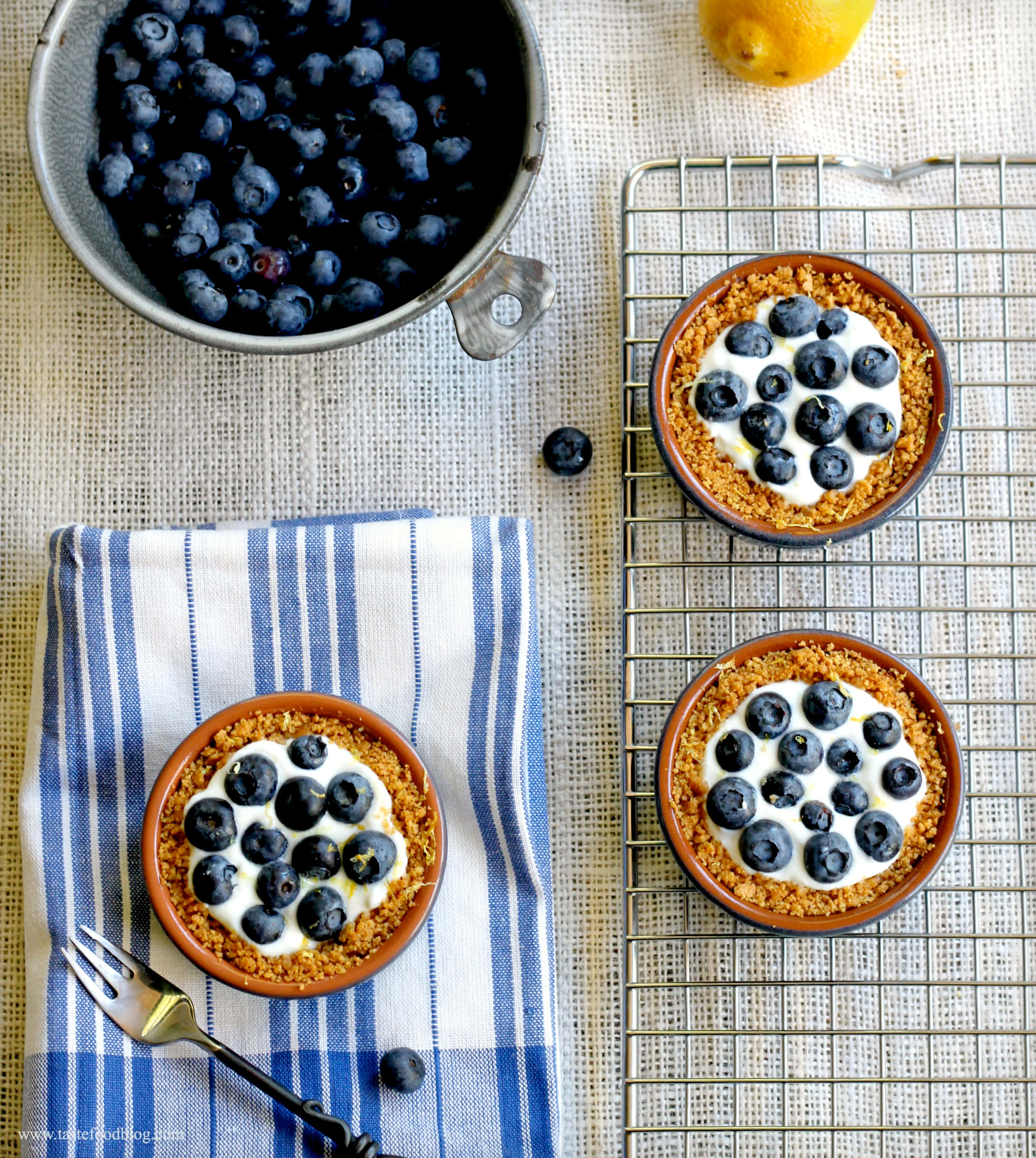 Blueberries Tart 桌布 壁紙 — 三個藍莓乳酪撻放在冷卻架上和條紋布上，旁邊有一碗新鮮漿果和檸檬。