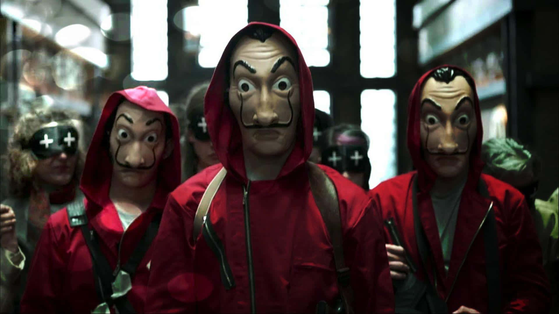 Money Heist 桌布 壁紙 — 三個身穿標誌性紅色連帽衫、戴著達利面具的人物站在光線昏暗的城市小巷中，身後是模糊的商店門面。