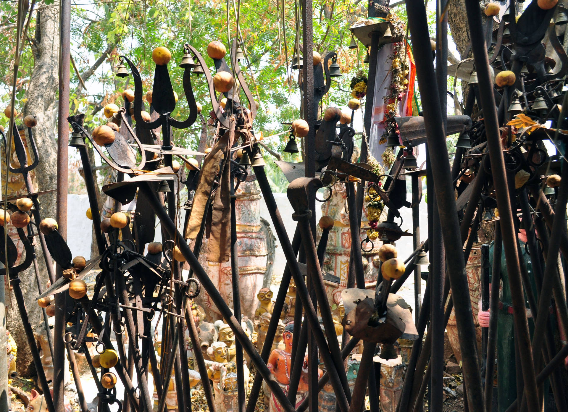 一個神聖的花園，充滿金屬柱、鈴鐺和金色球體，在明亮的陽光下。