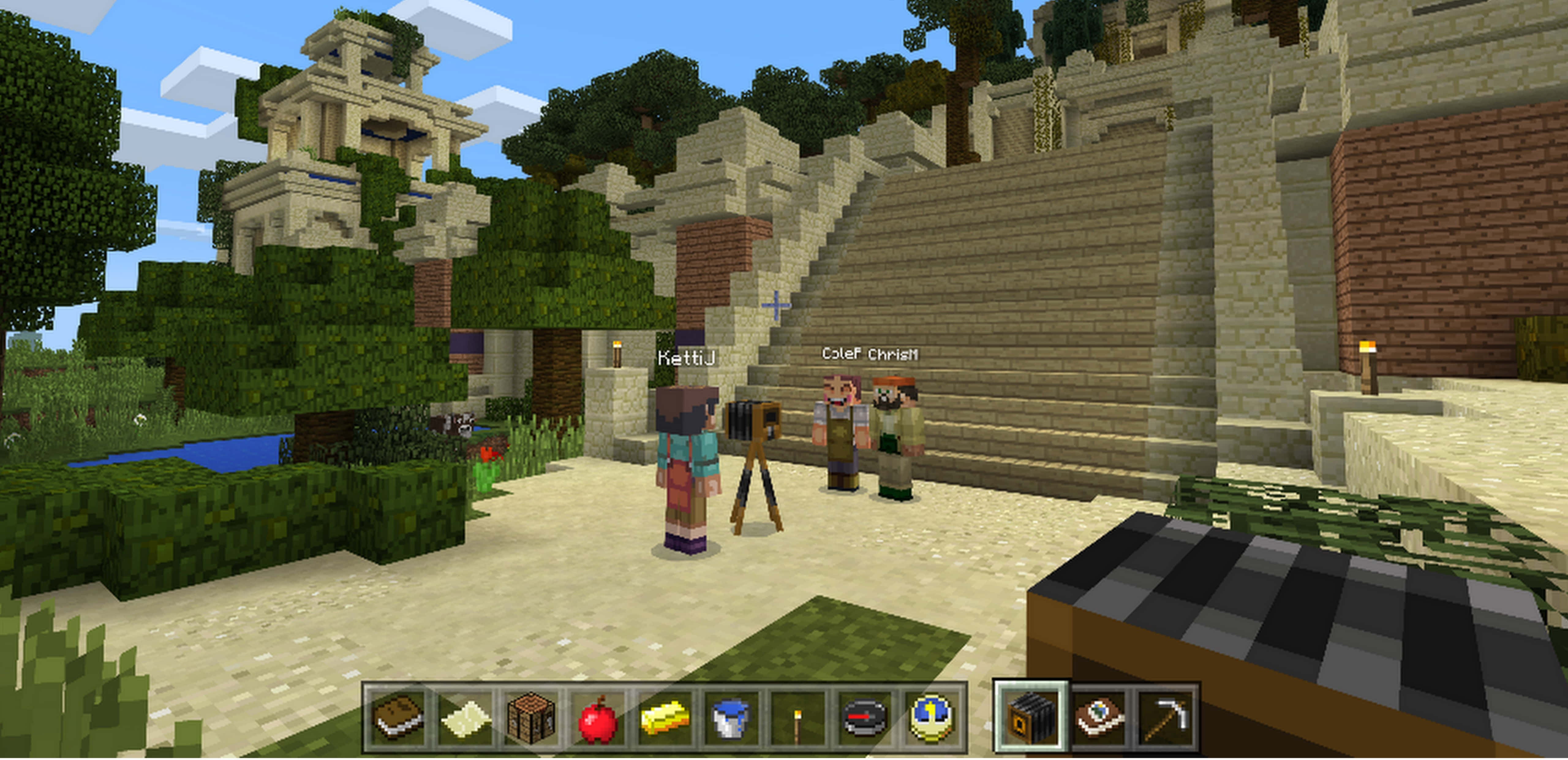 Minecraft Education Edition 桌布 壁紙 — 三名Minecraft玩家站在一座石廟前，周圍有茂密的樹木和清澈的藍天。