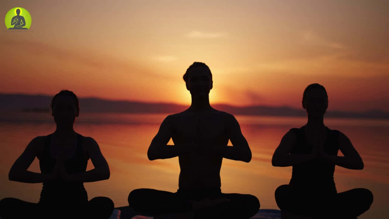 三人在日落時分在水邊以剪影冥想